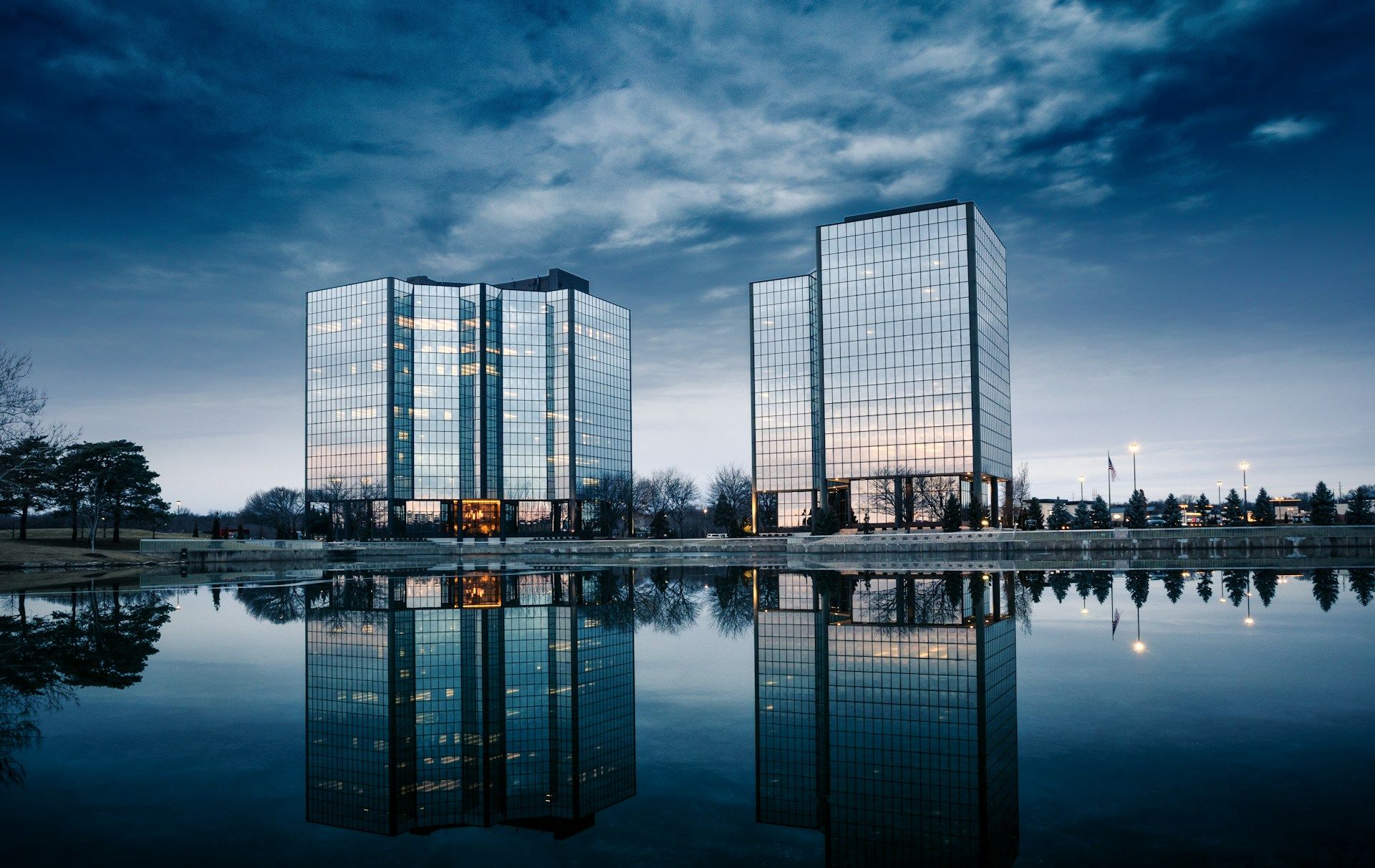 Two glass high rise buildings reflecting on a pond at blue hour on a cloudy morning in  Overland Park, KS, USA