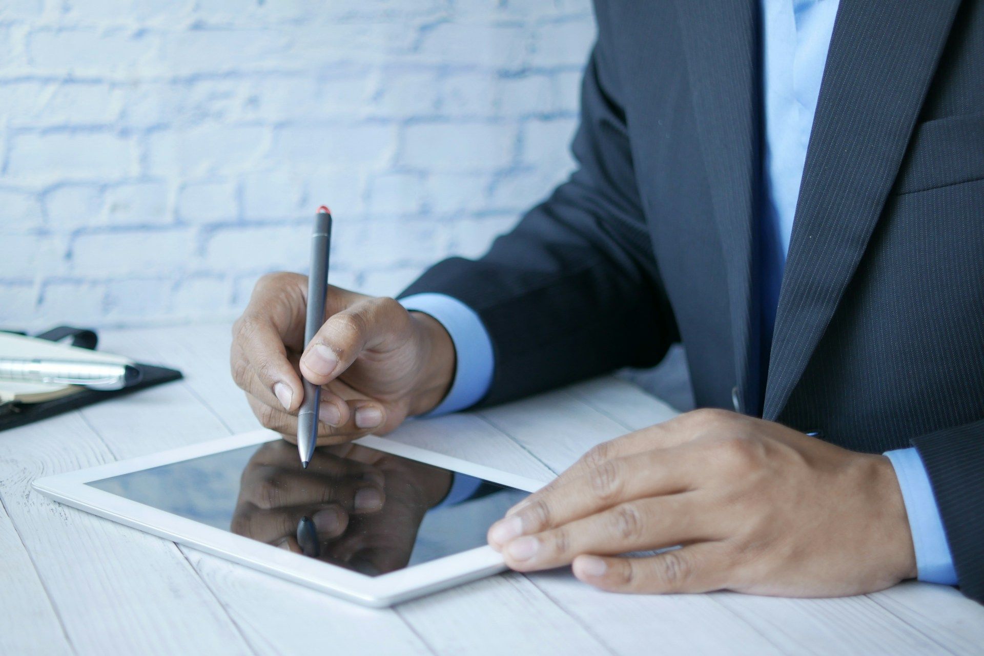 Man in suit writing on a tablet