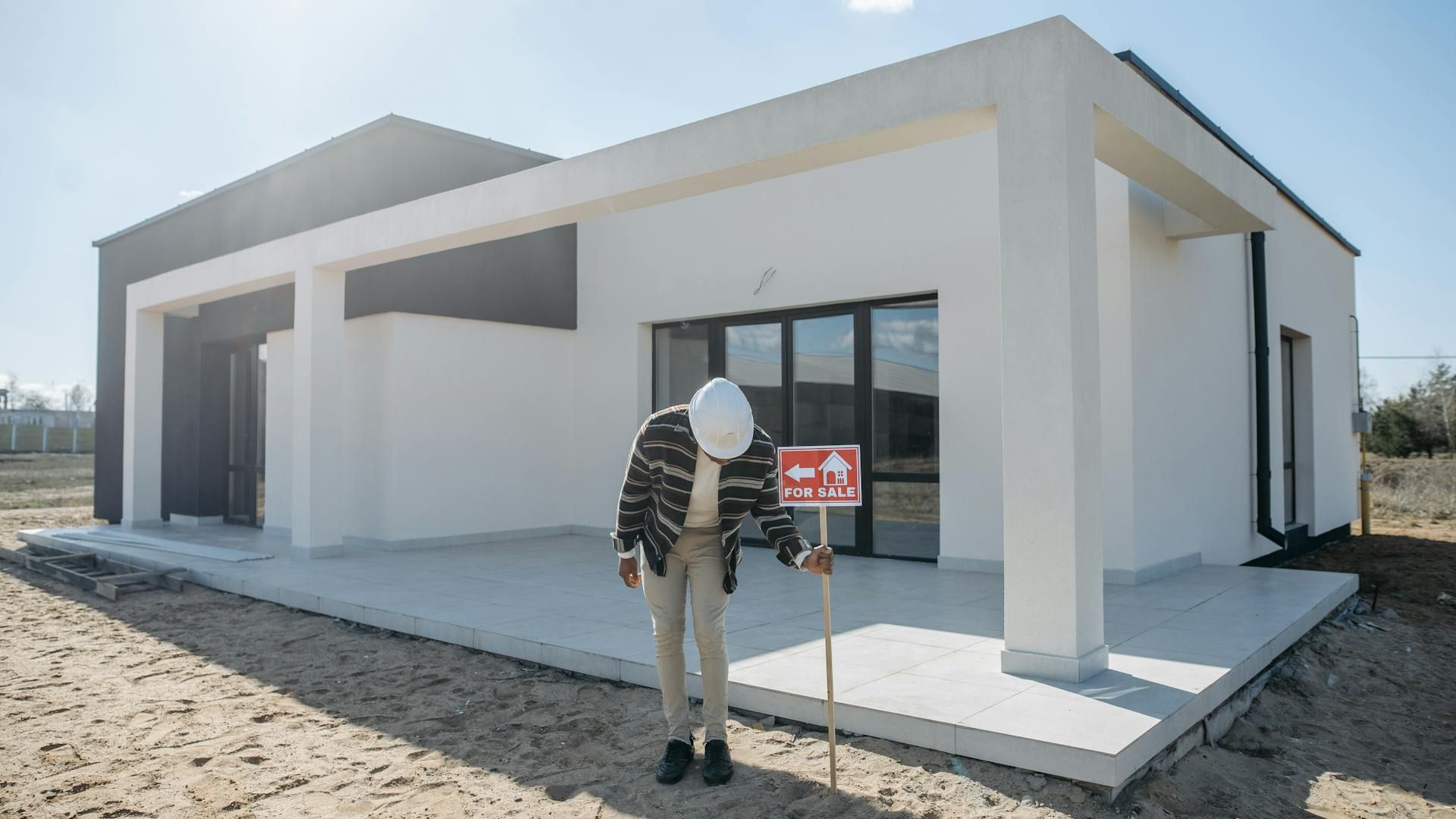 A Man Posting a For Sale Sign Near a House