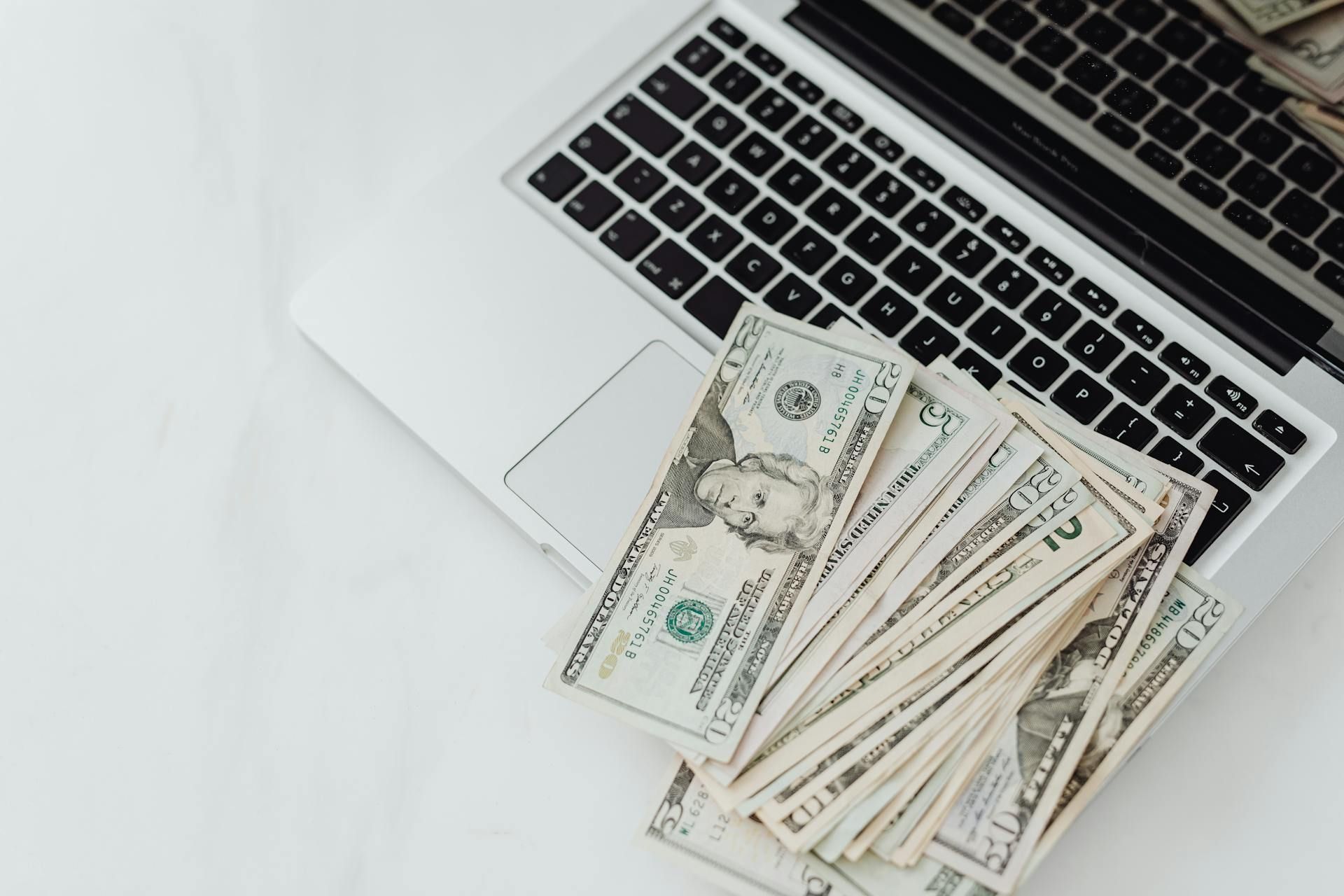 Close-Up Photo of Banknotes on Top of a Laptop's Keyboard