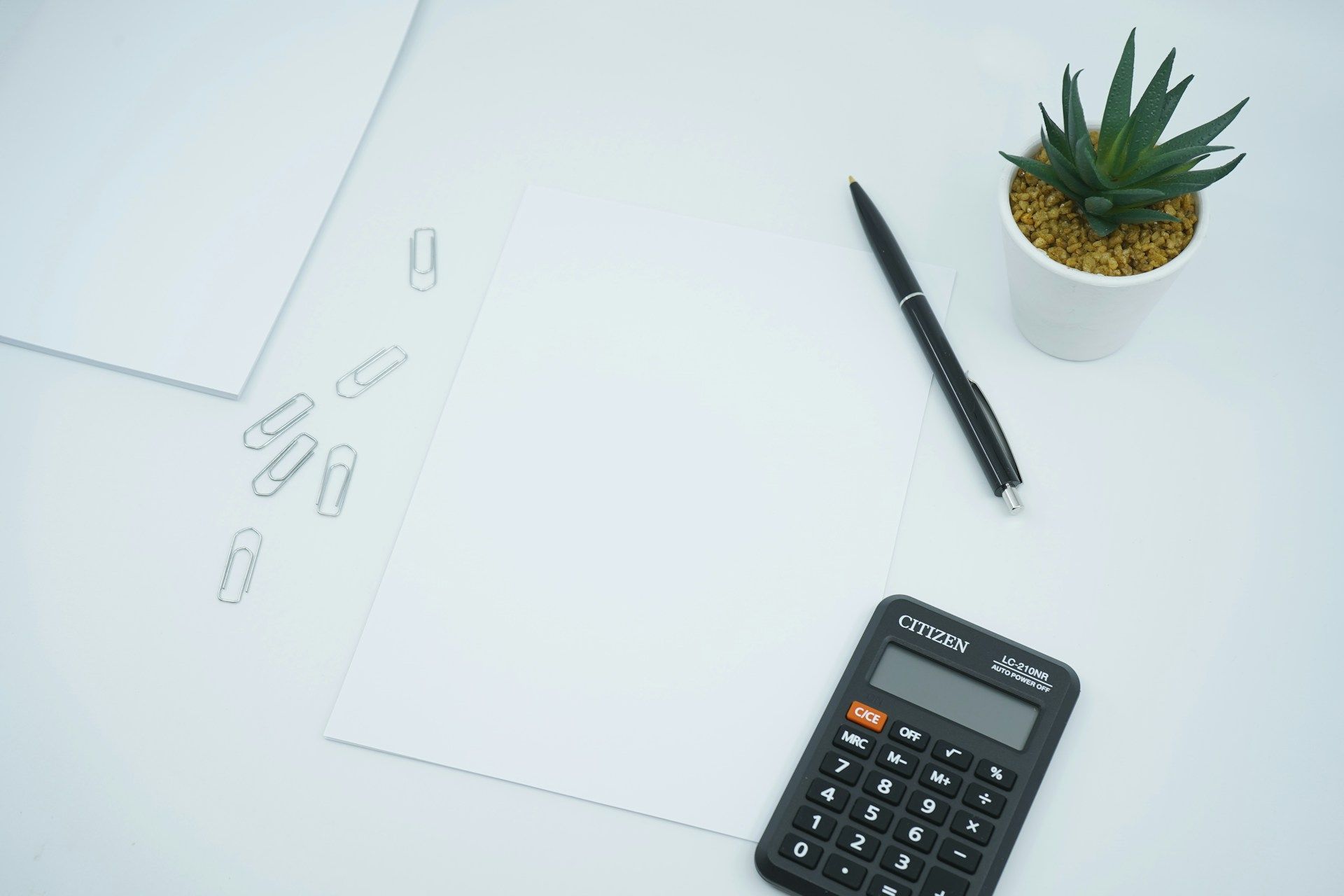 A photo of a calculator on top of a blank paper with a pen to the side