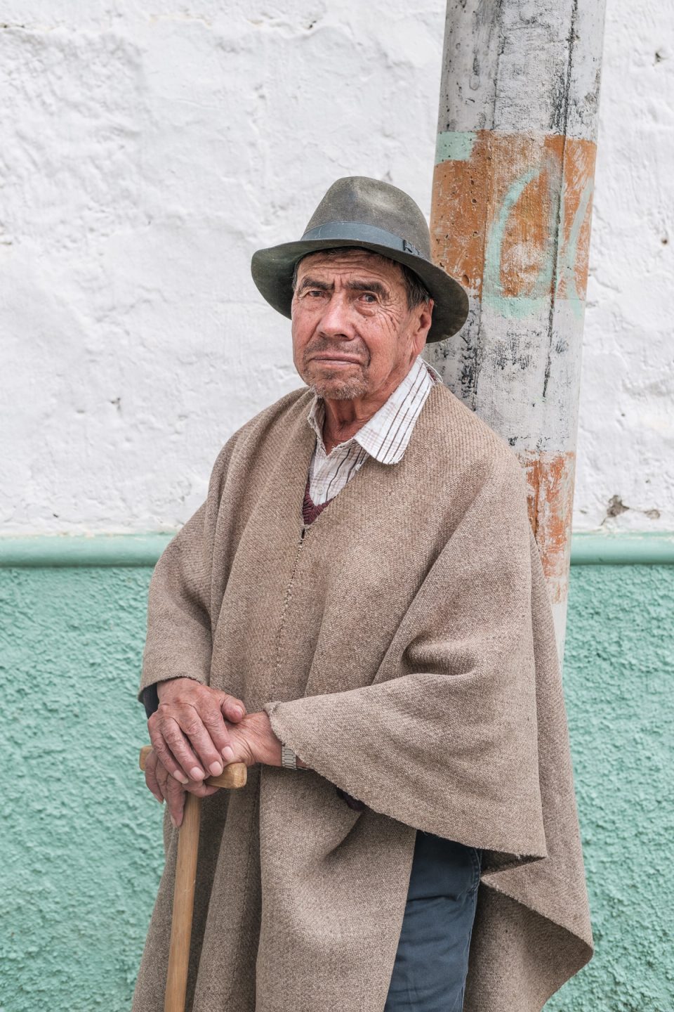 Older man standing in a poncho and hat