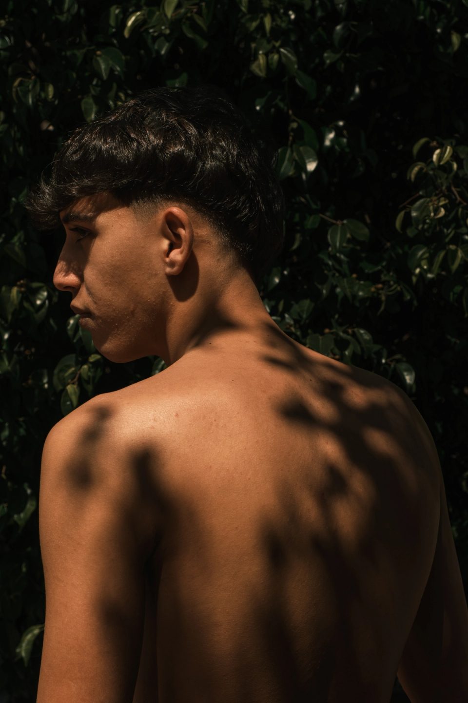 Shirtless young man seen from behind in sunlight