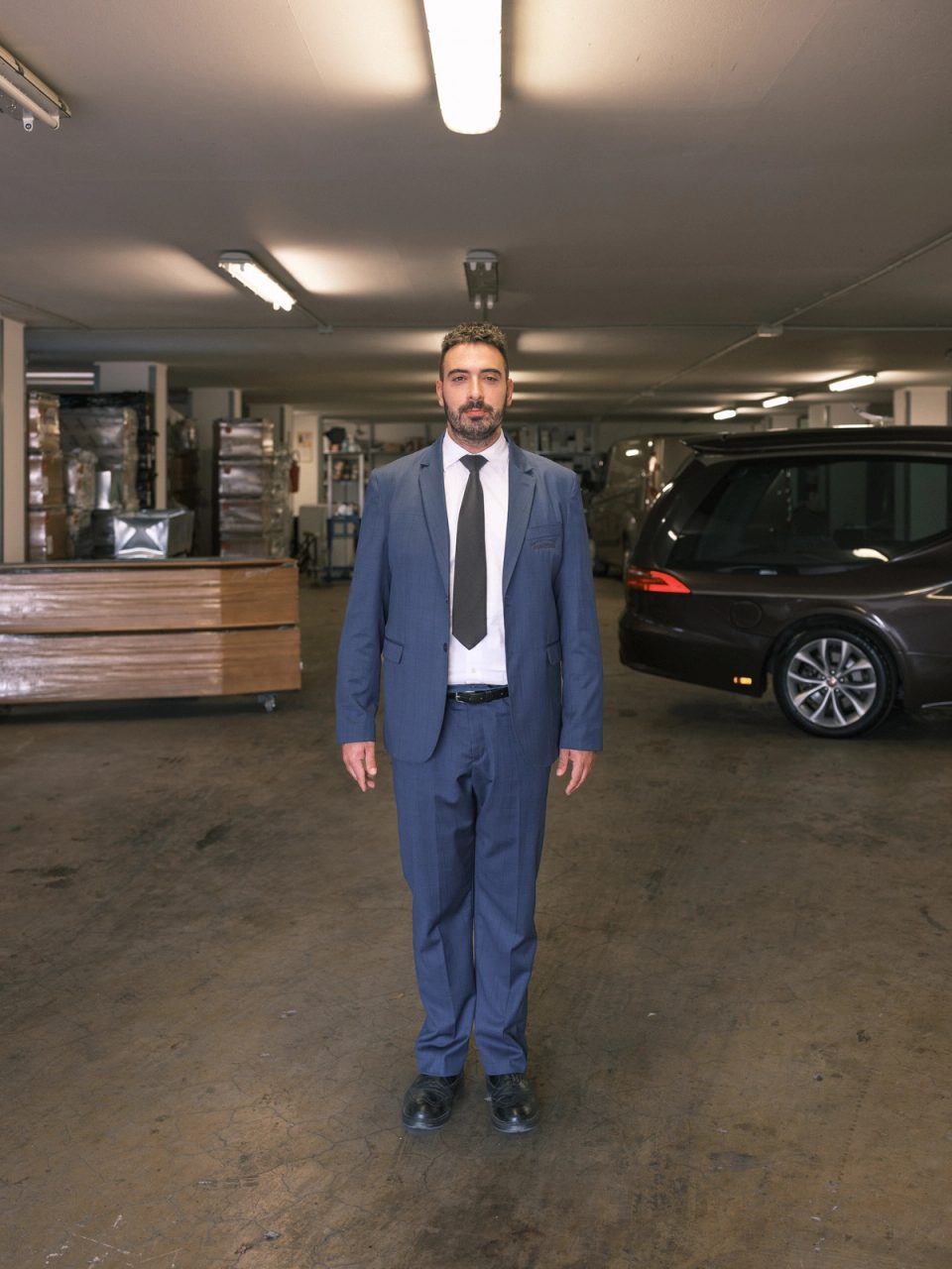 Funeral home worker standing beside a hearse
