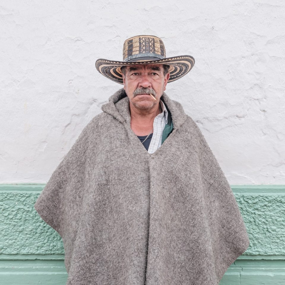 Older man wearing a poncho and woven hat
