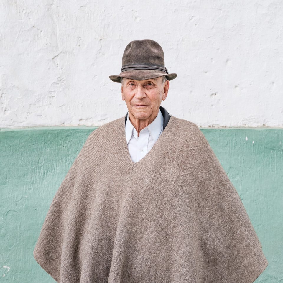 Older man wearing a poncho and brown hat
