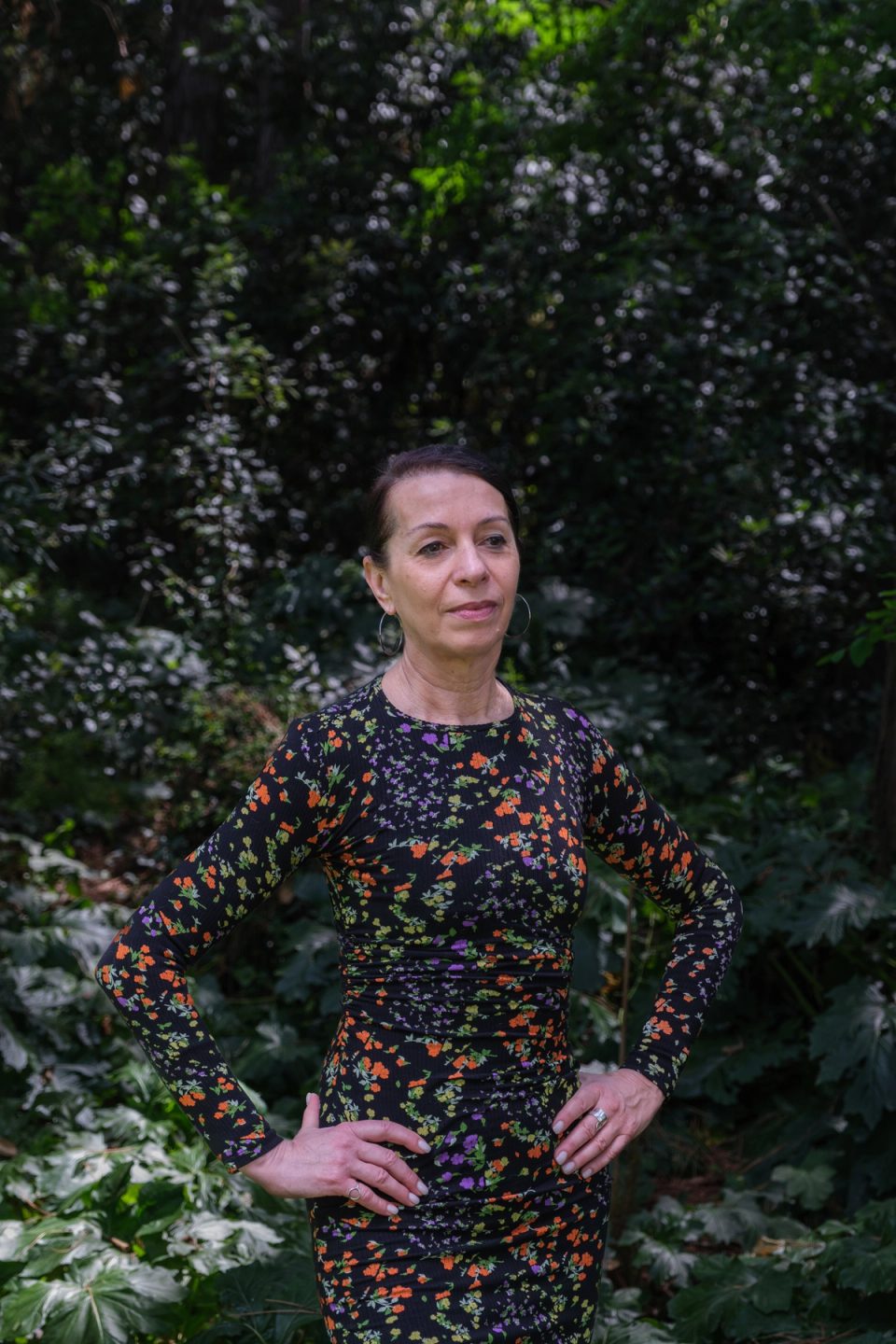 Woman standing outdoors in front of dark greenery