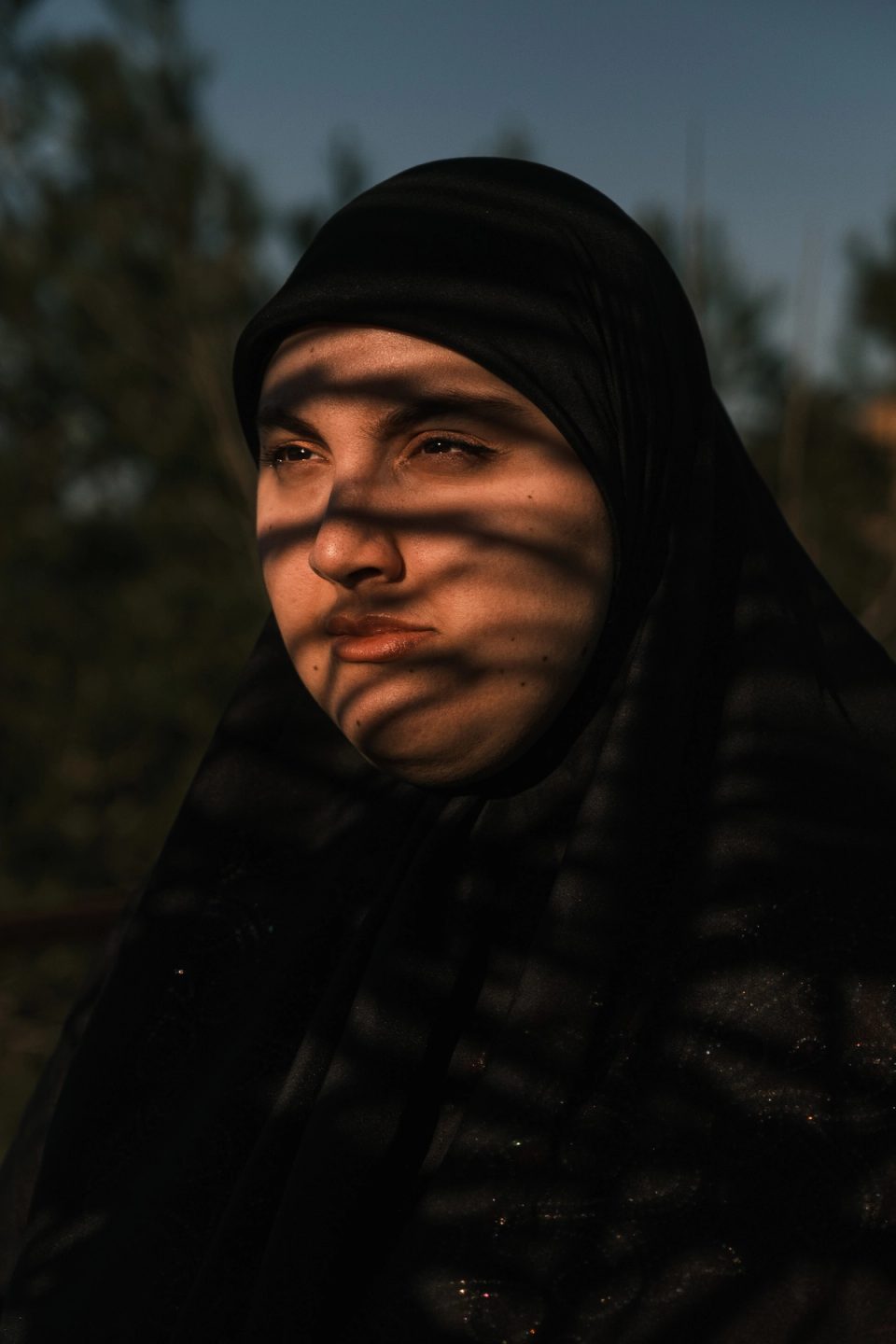 Woman wearing a black headscarf in striped sunlight