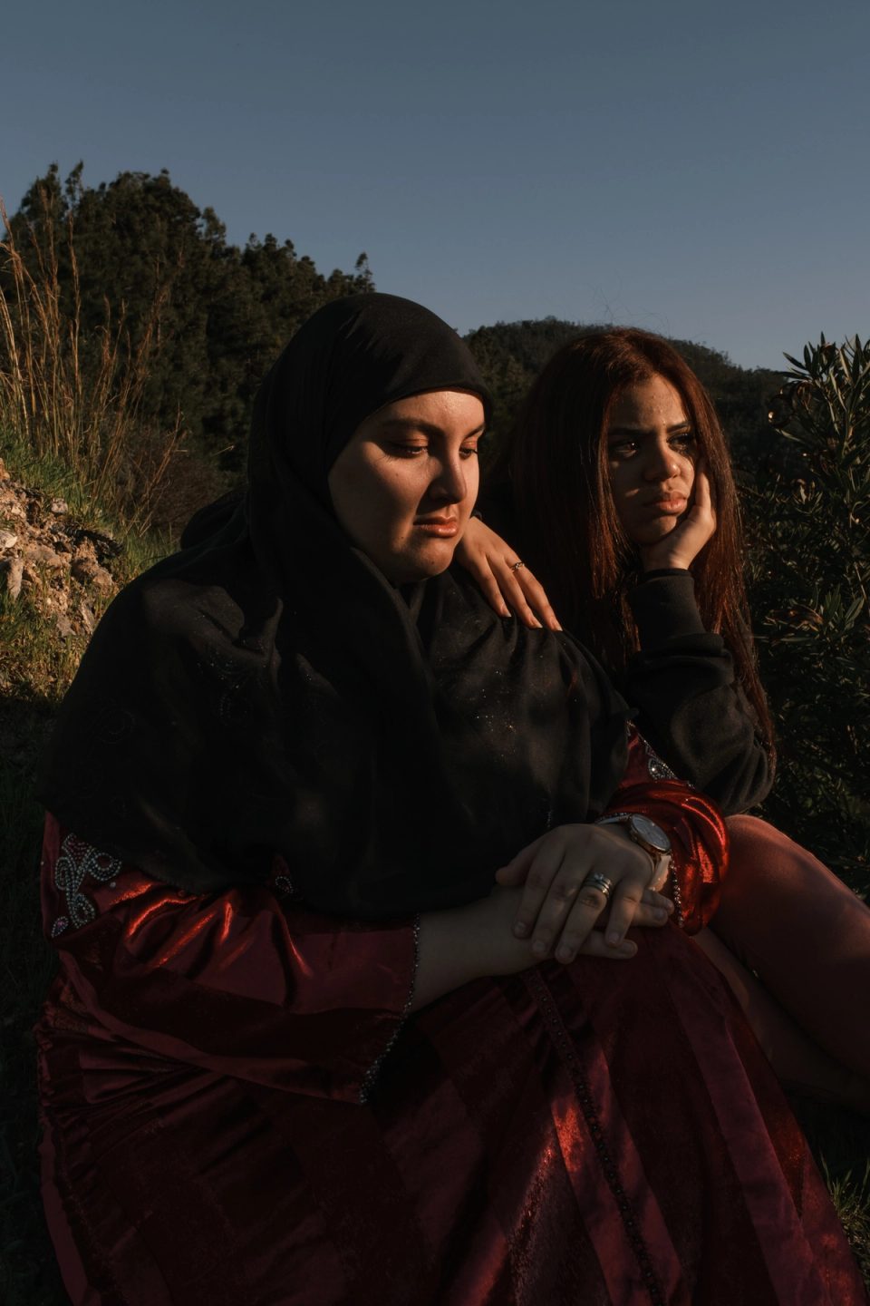 Two women sitting together outdoors in sunlight