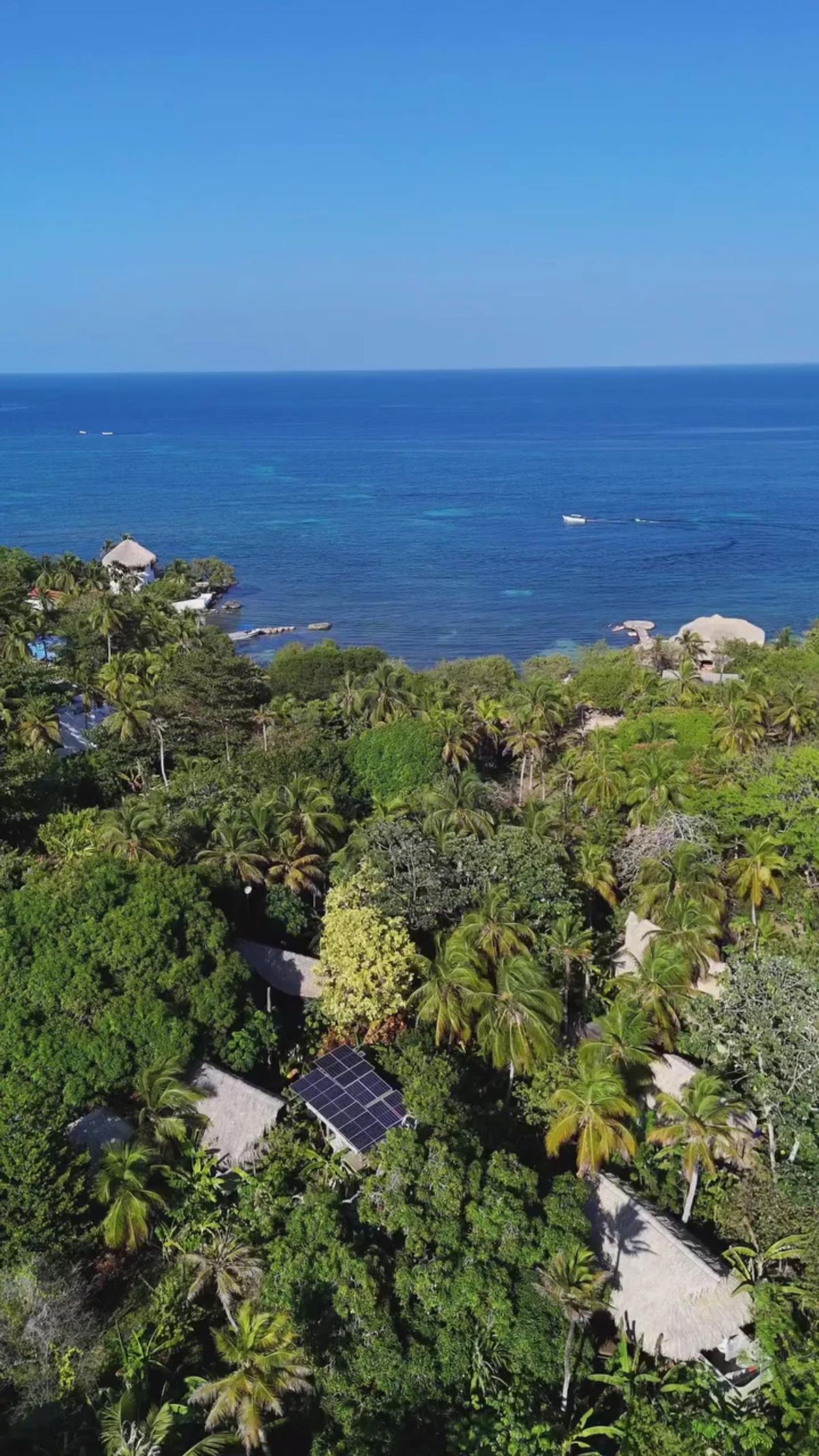 Vista aérea de la isla: selva, casas y mar Caribe