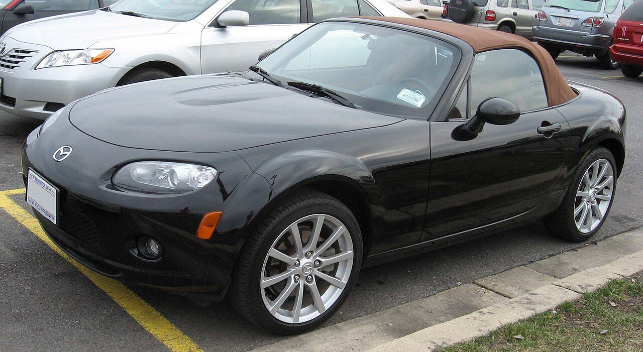 Black Mazda MX-5 NC with a tan soft top