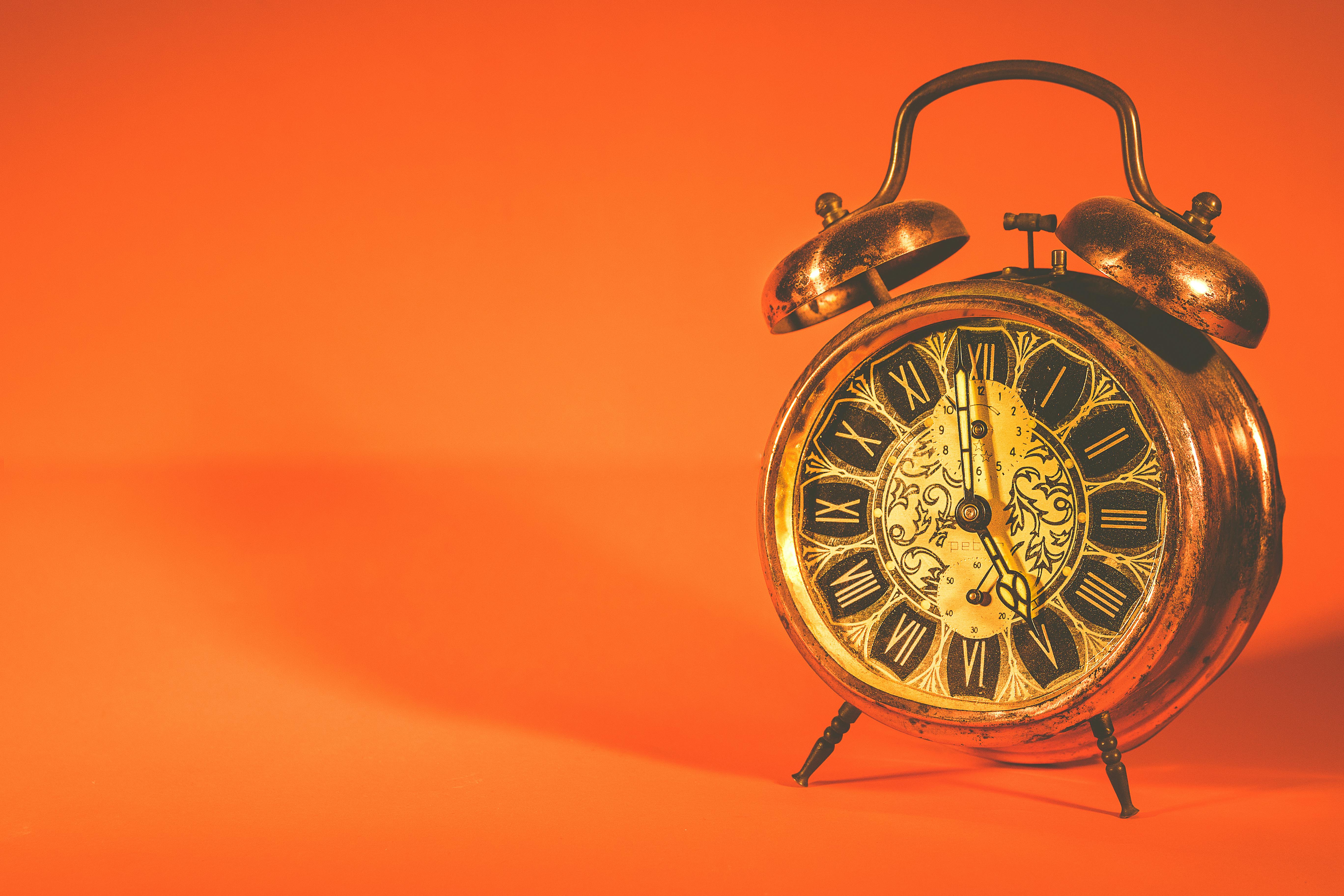 Vintage alarm clock on orange background