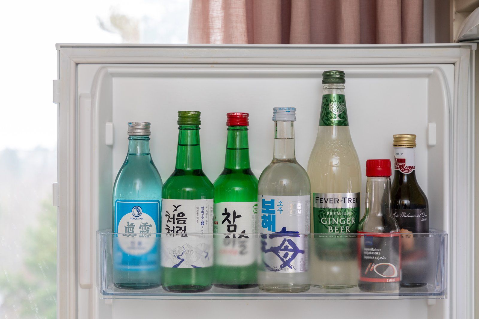 Dãy chai soju màu xanh xếp trong cánh tủ lạnh