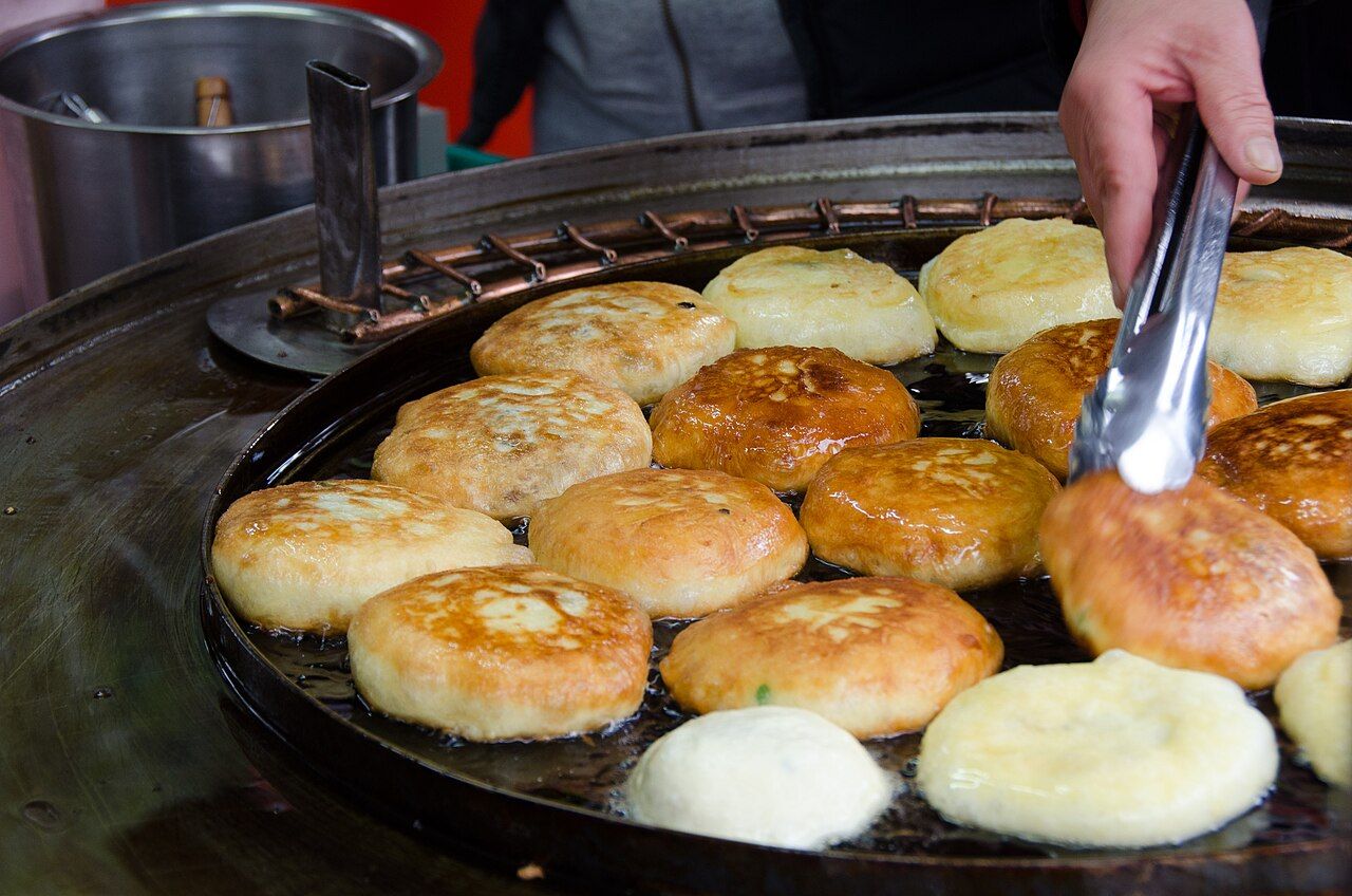 Bánh hotteok vàng giòn nóng hổi trên vỉ nướng