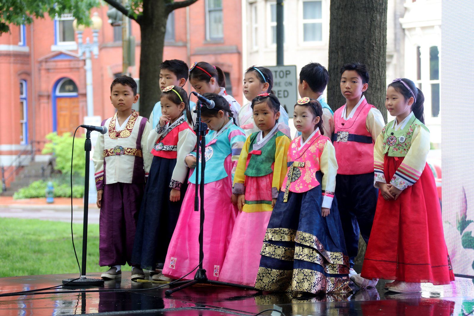 Một nhóm trẻ em mặc hanbok nhiều màu đứng hát trên sân khấu