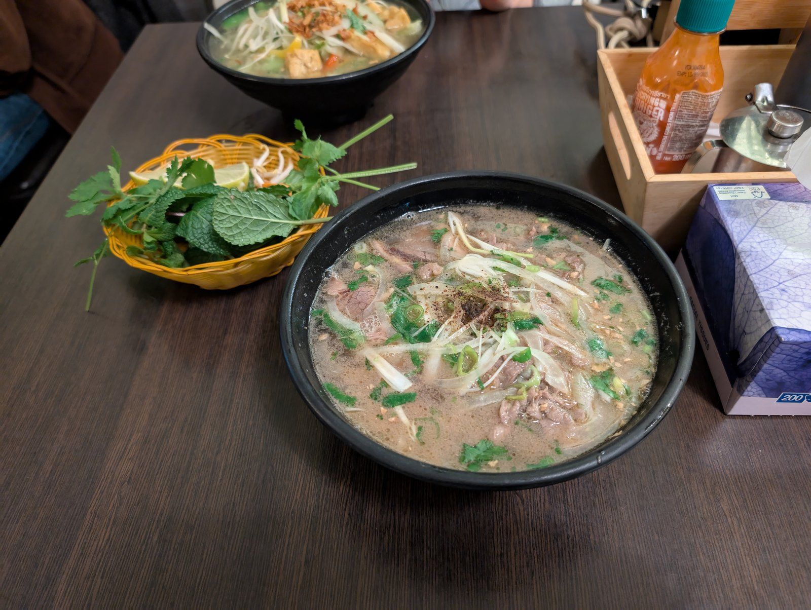 Tô phở bò Việt Nam nóng hổi với rau thơm bày trên bàn