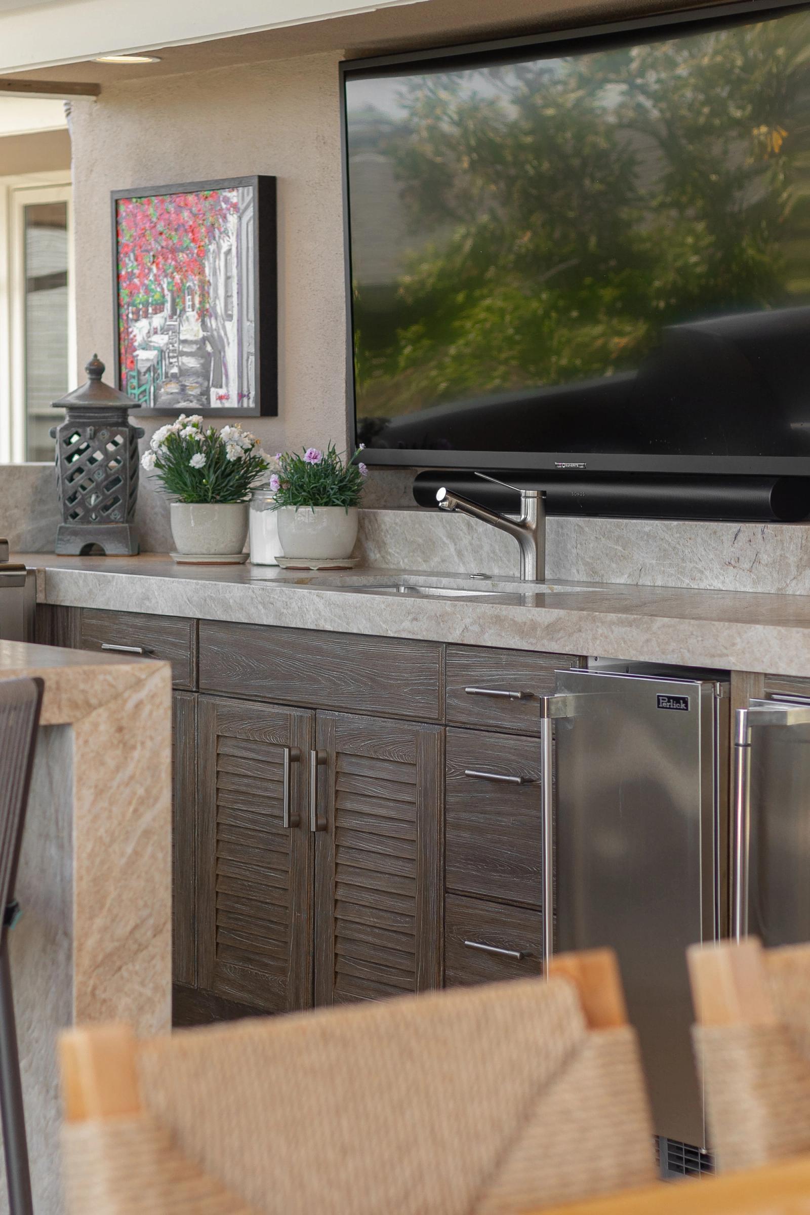 louvered cabinetry with sink and stainless steel fridge