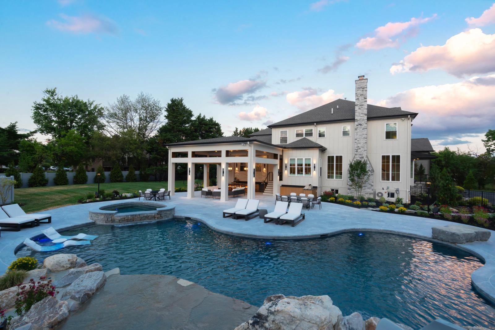 pool at dusk with a covered outdoor kitchen pavilion