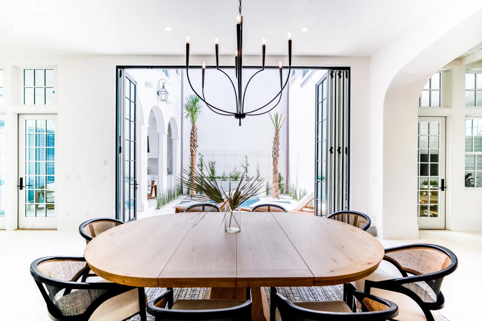 Oval wood dining table under a black chandelier