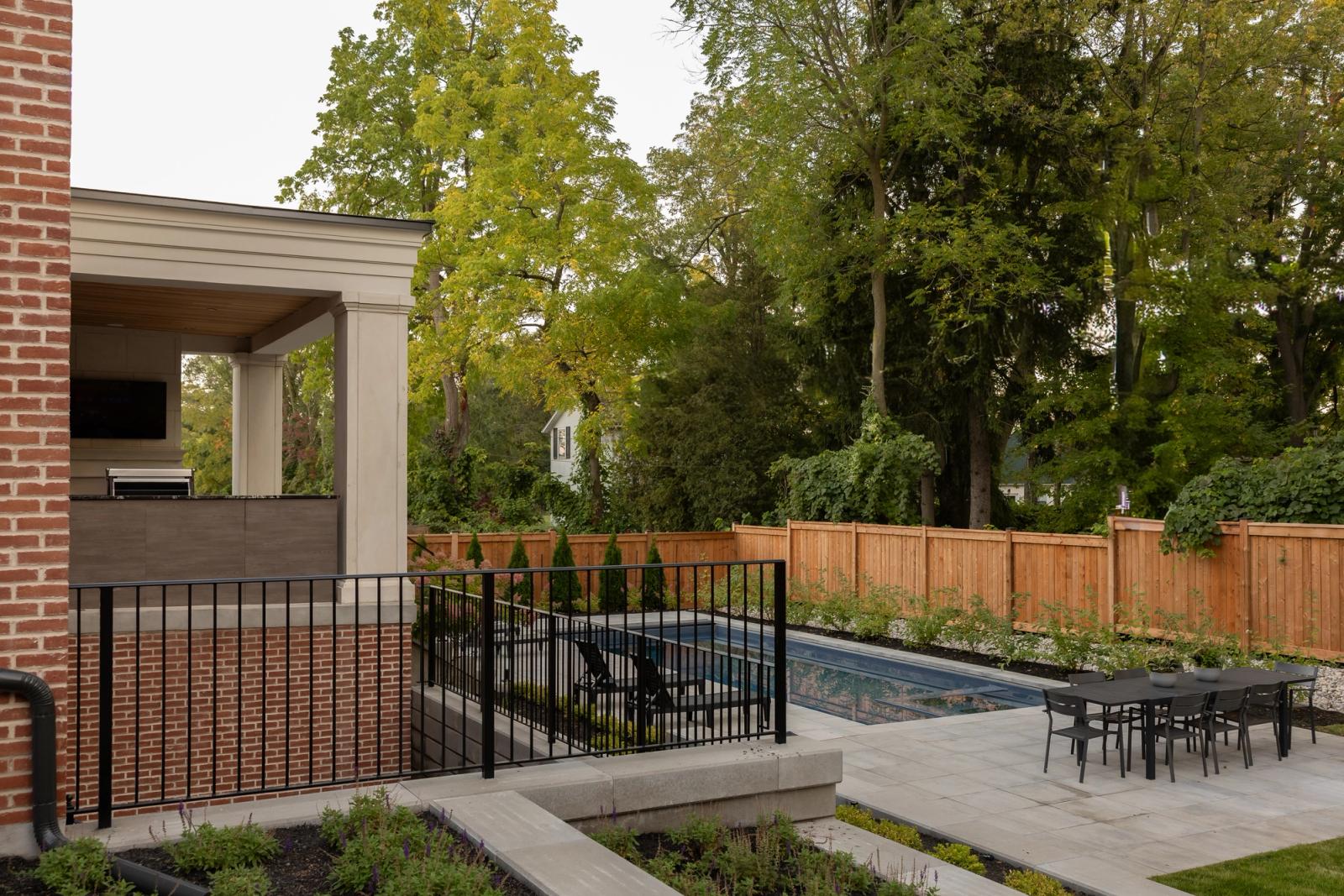 Covered pavilion kitchen with grill and wall TV beside a pool