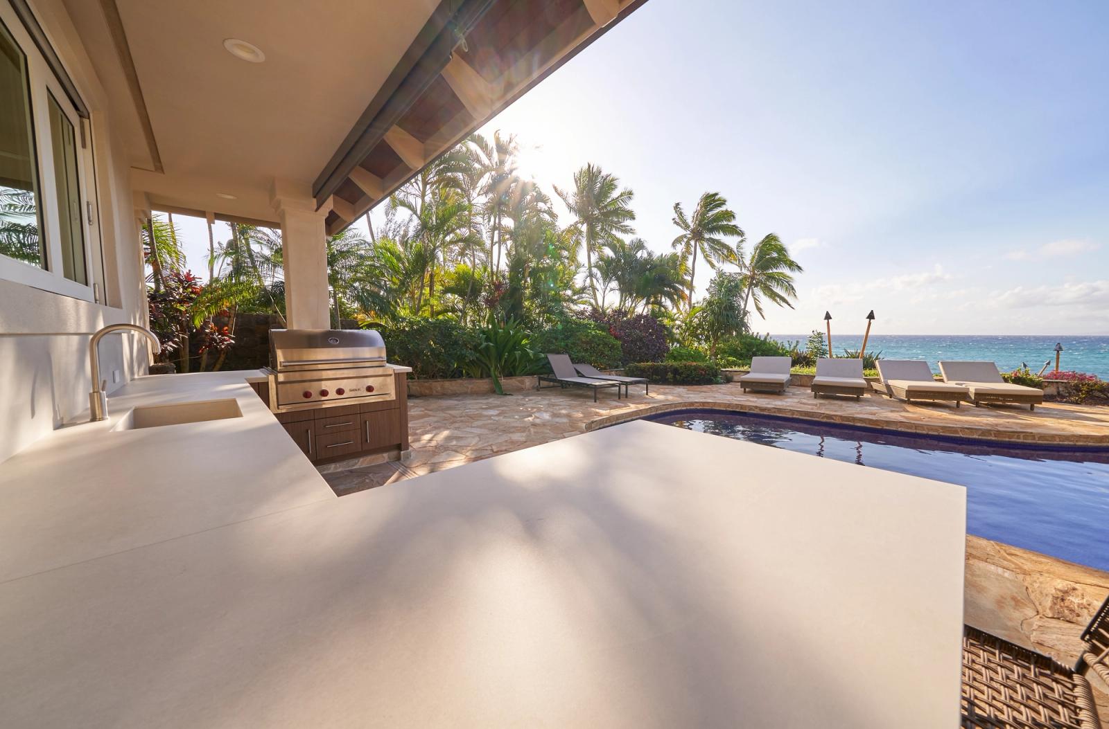 Oceanfront Hawaii lanai with a built-in grill in pale cabinetry beside a pool
