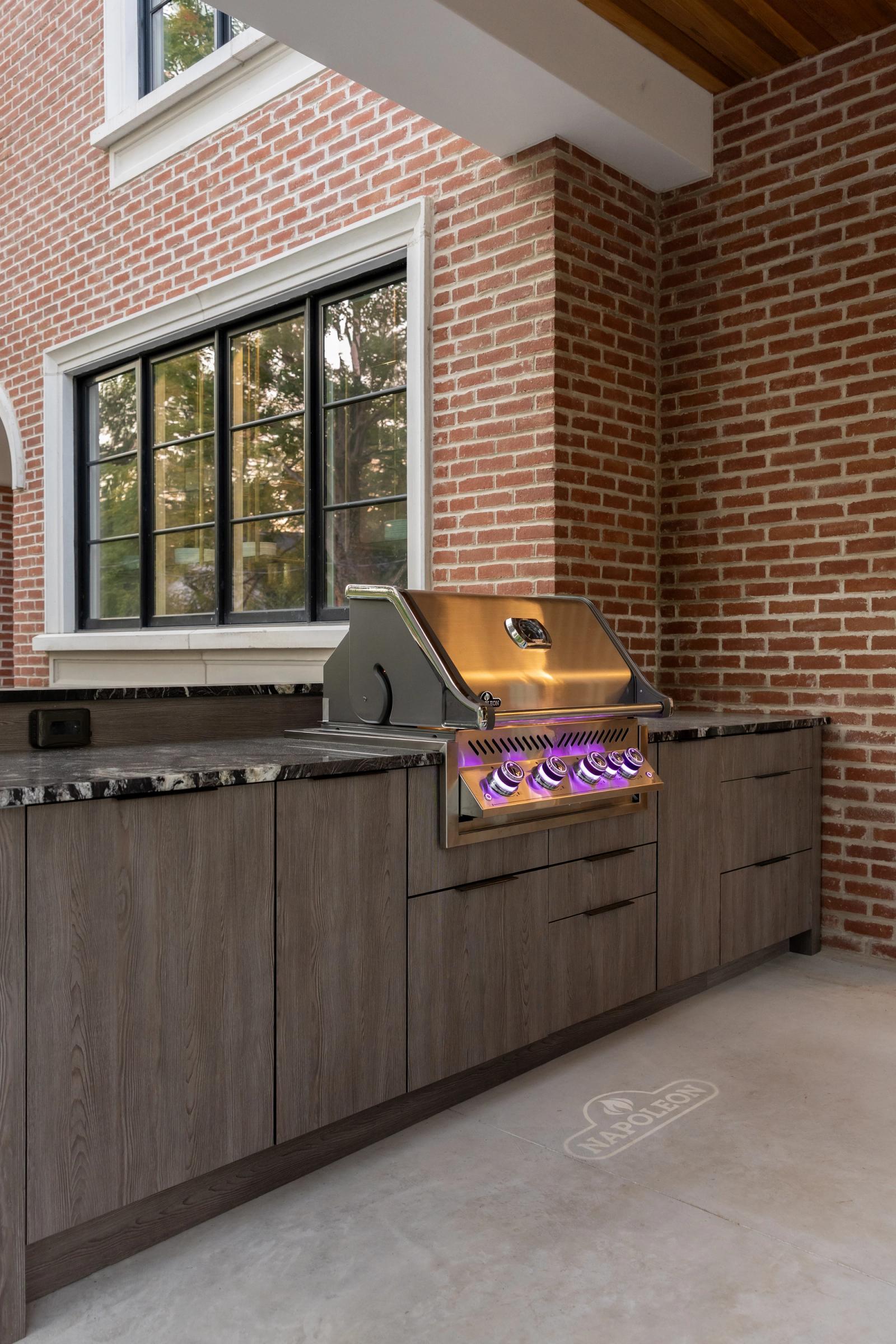 euro cabinetry on porch beside brick home with built in grill