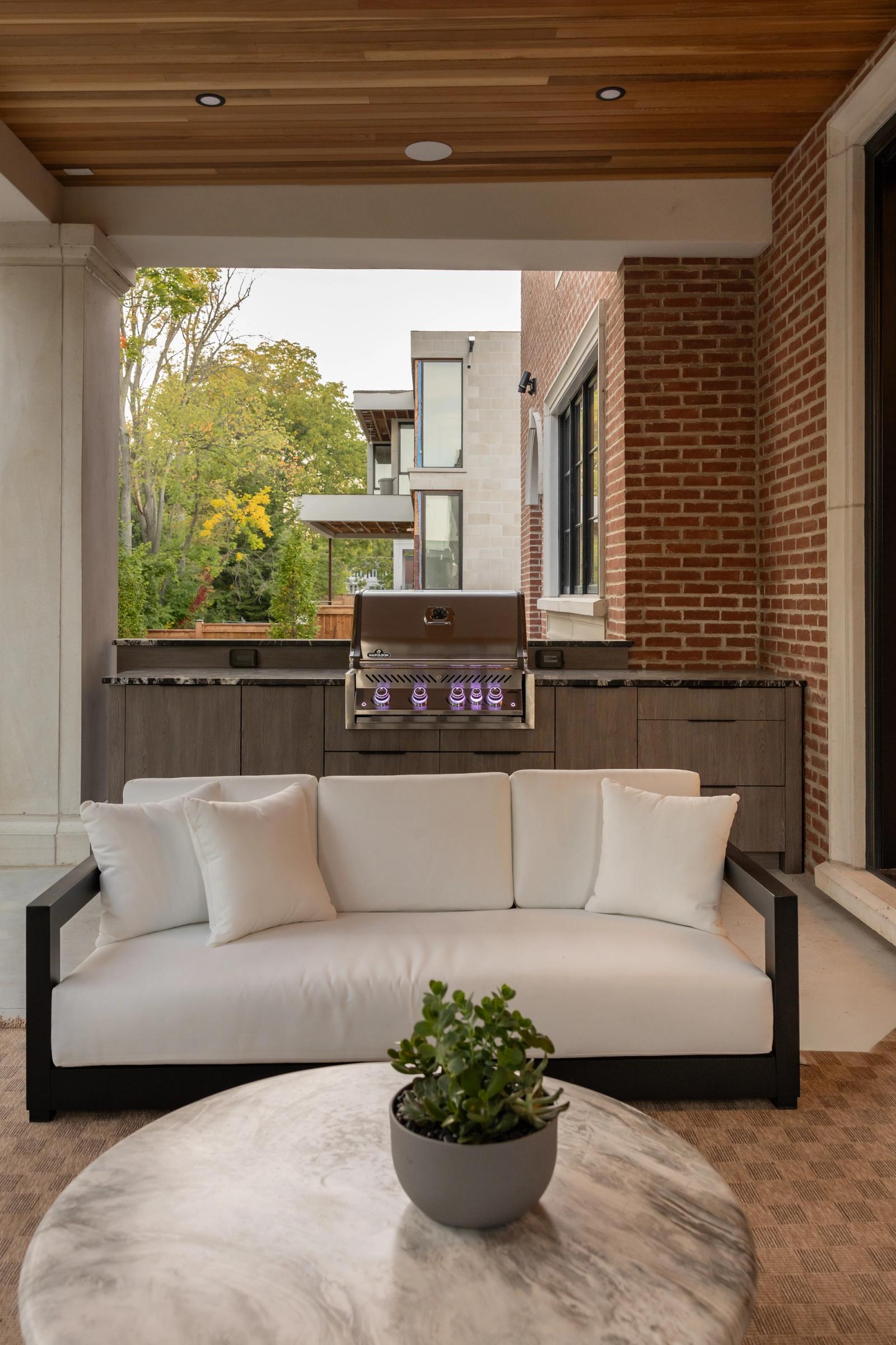 covered porch lounge with white sofa and outdoor cabinets for built in grill