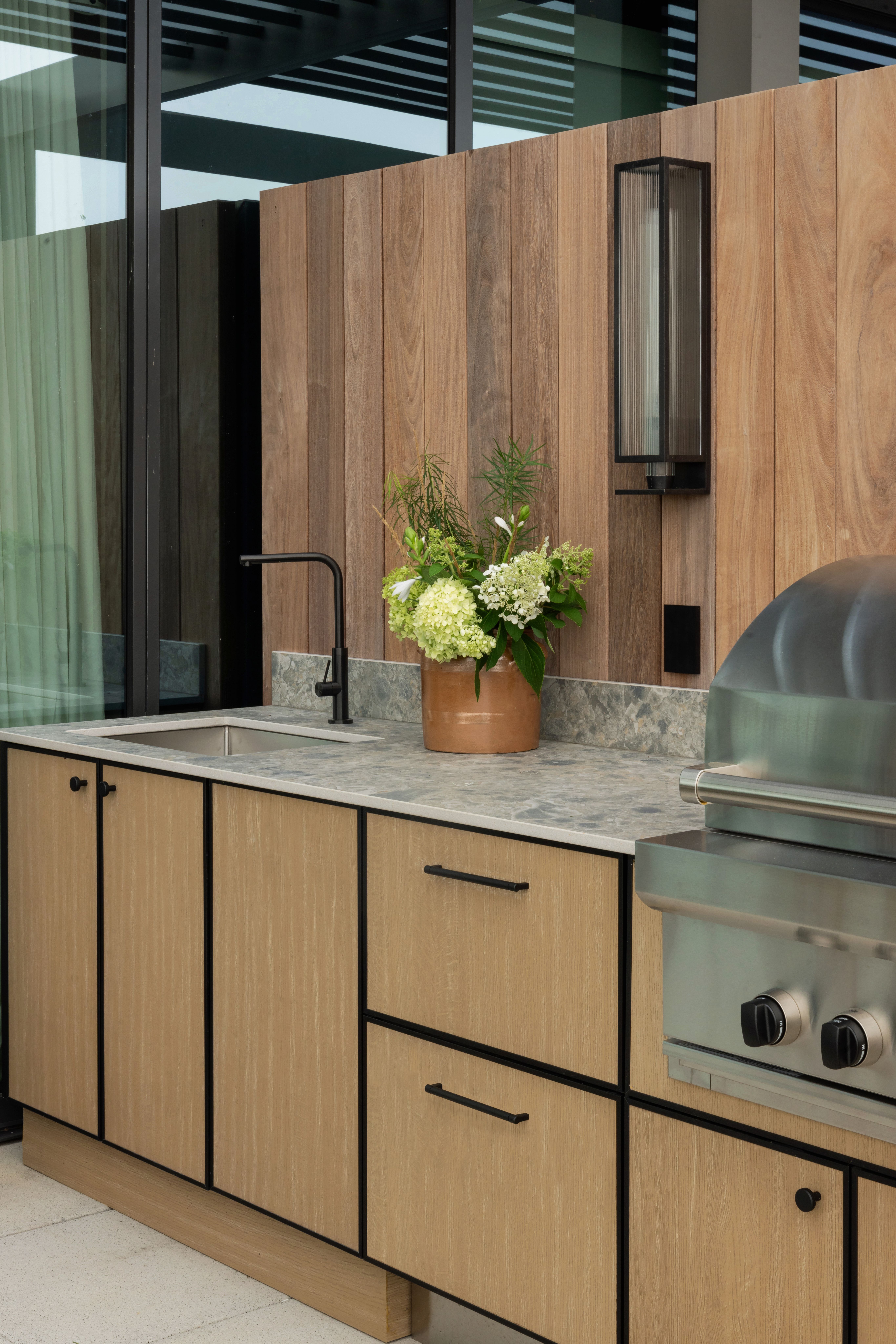 close up of a natural looking oak outdoor kitchen with panel ready fridge