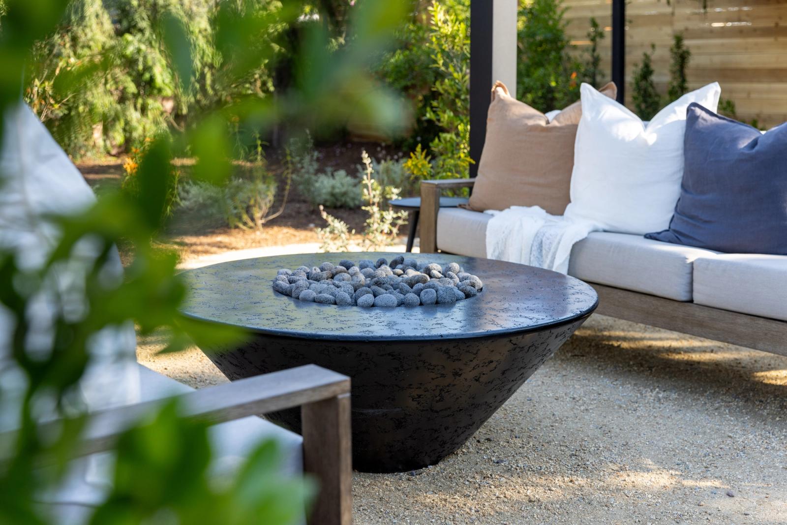 round fire bowl with river stones and outdoor kitchen