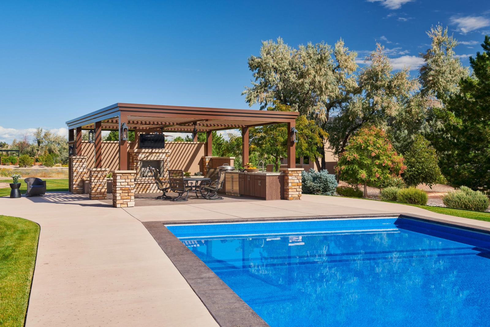 Poolside pergola kitchen built-in grill and dining seating under sun