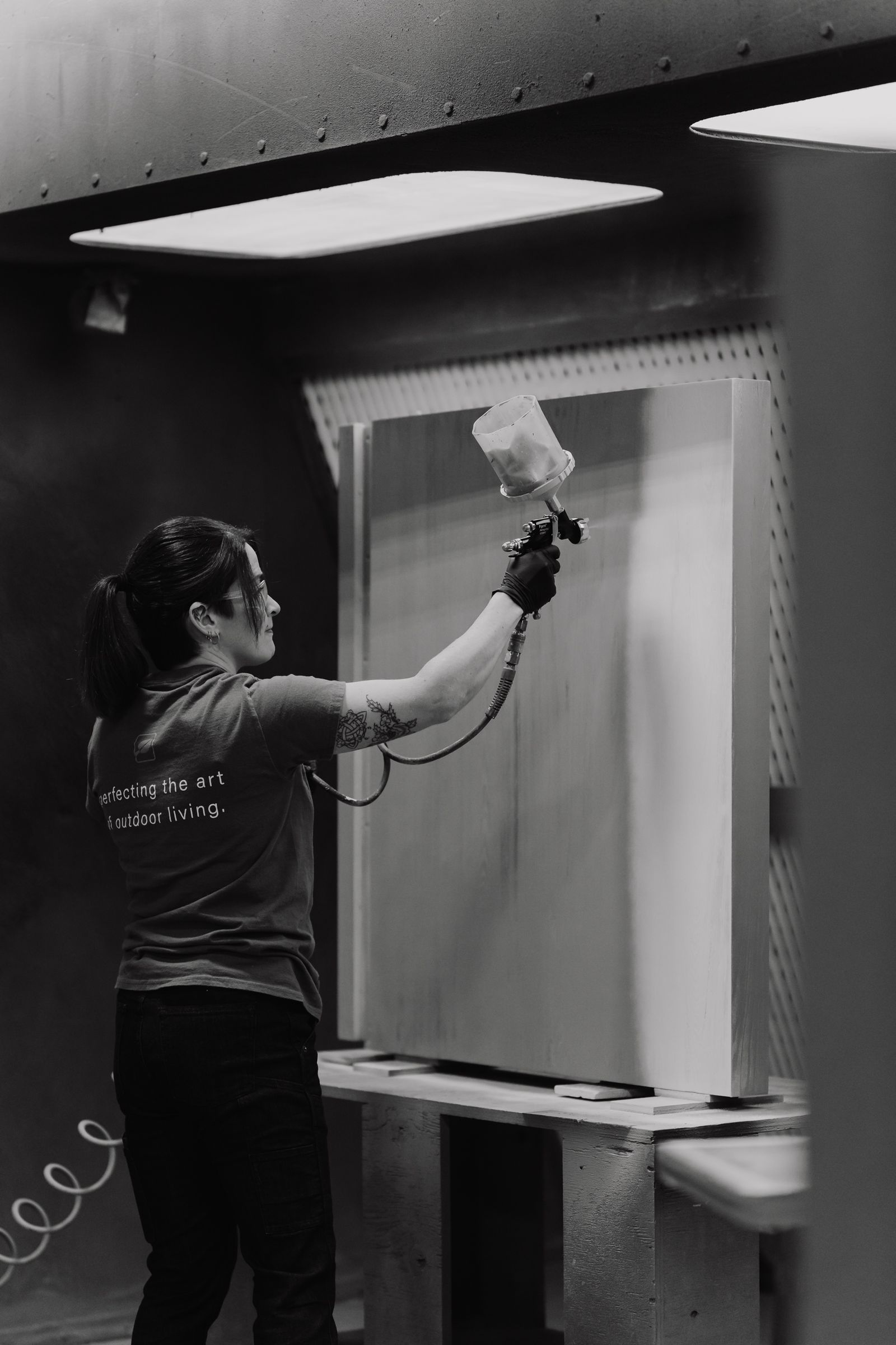 Craftsperson spray-finishing a cabinet door in the NatureKast finishing booth