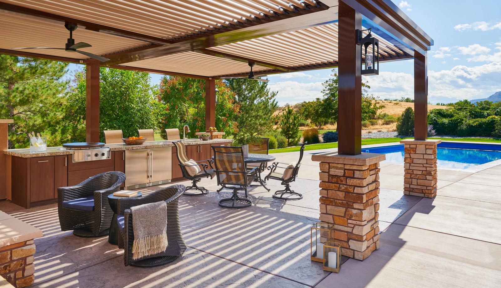 Poolside outdoor kitchen and dining area under a louvered pergola