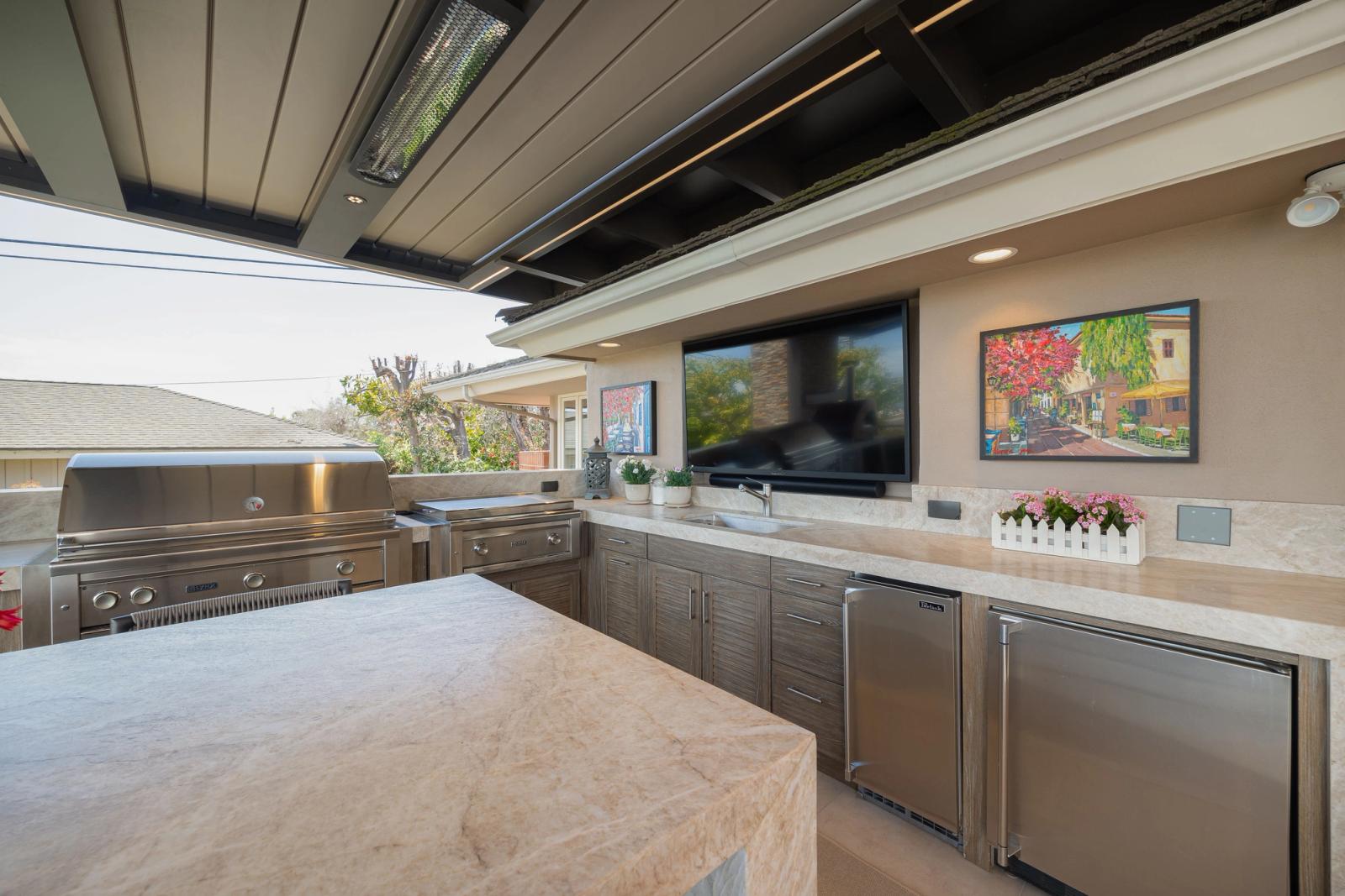Louvered patio kitchen in weathered grey cabinetry with a grill and fridge