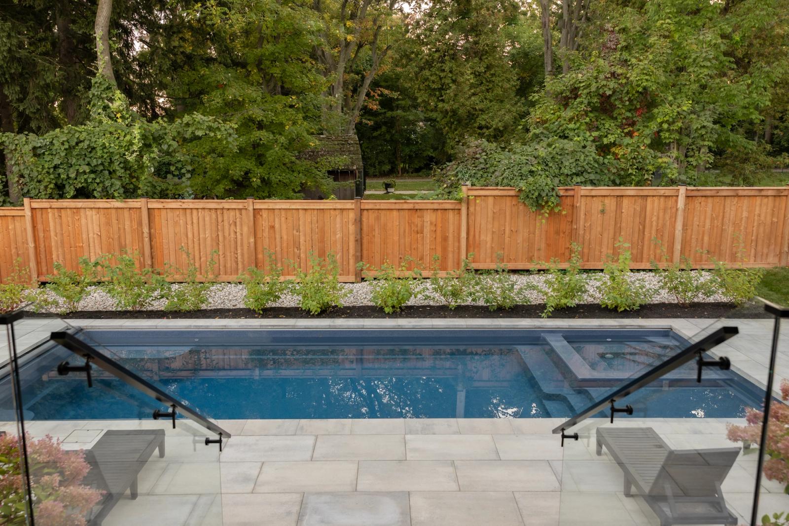 Rectangular pool beside an outdoor kitchen on stone patio