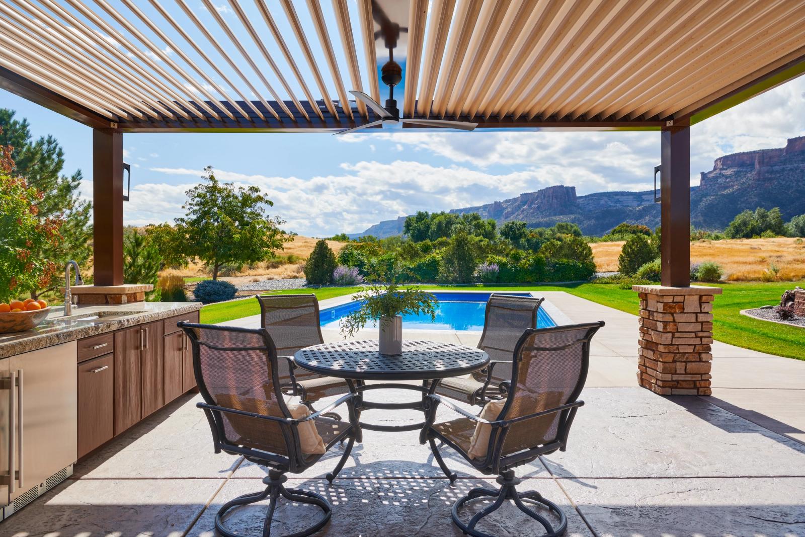 outdoor kitchen and dining space under louvered pergola in desert