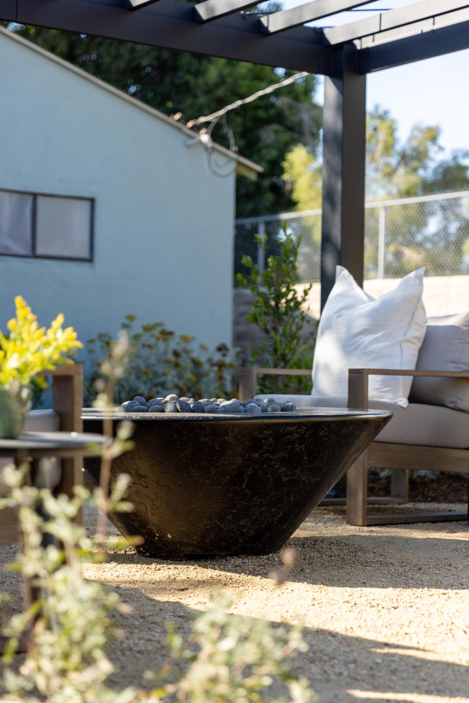 black concrete firepit in backyard with lounge seating