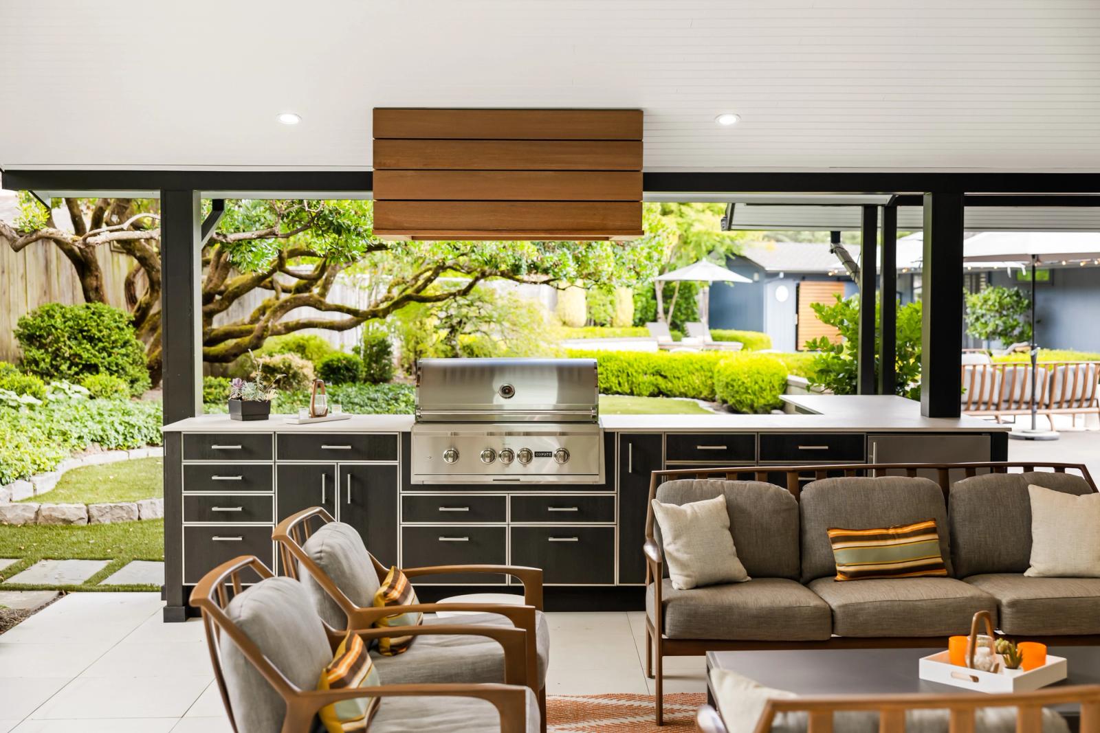 outdoor kitchen with dark cabinetry opening onto a garden