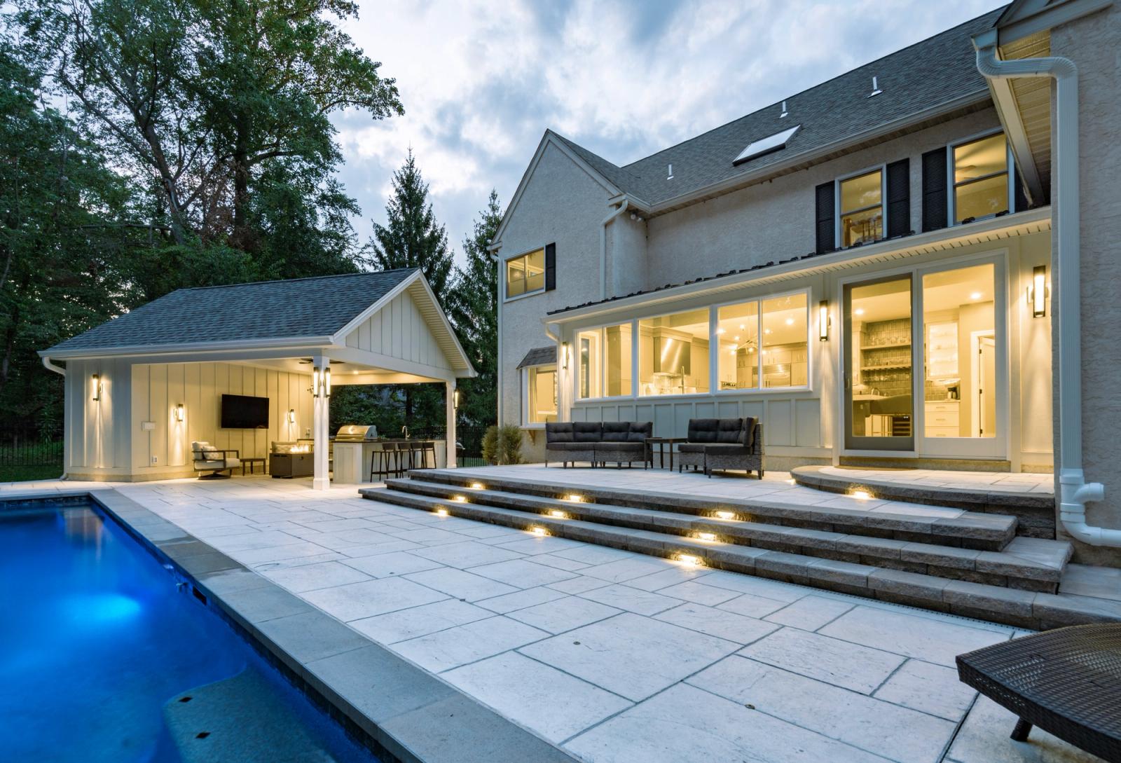 Home at dusk with a lit pool covered patio kitchen
