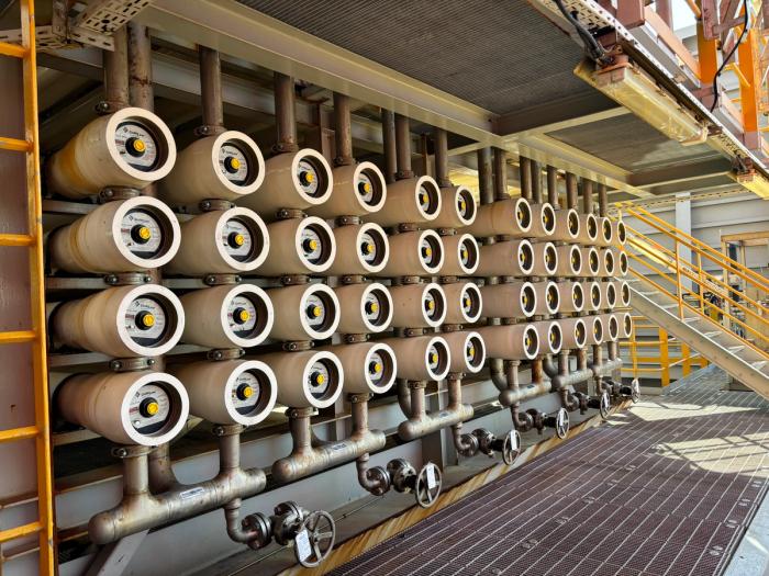 Four stacked rows of horizontal membrane pressure vessels on an offshore skid, joined by a manifold of pipework and hand-wheel valves.