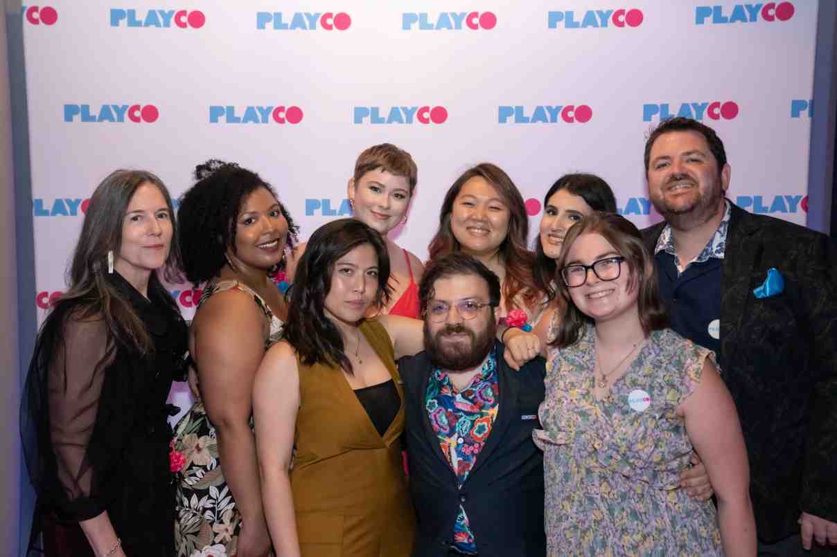 The PlayCo staff takes a group picture in front of the step-and-repeat, all beaming.