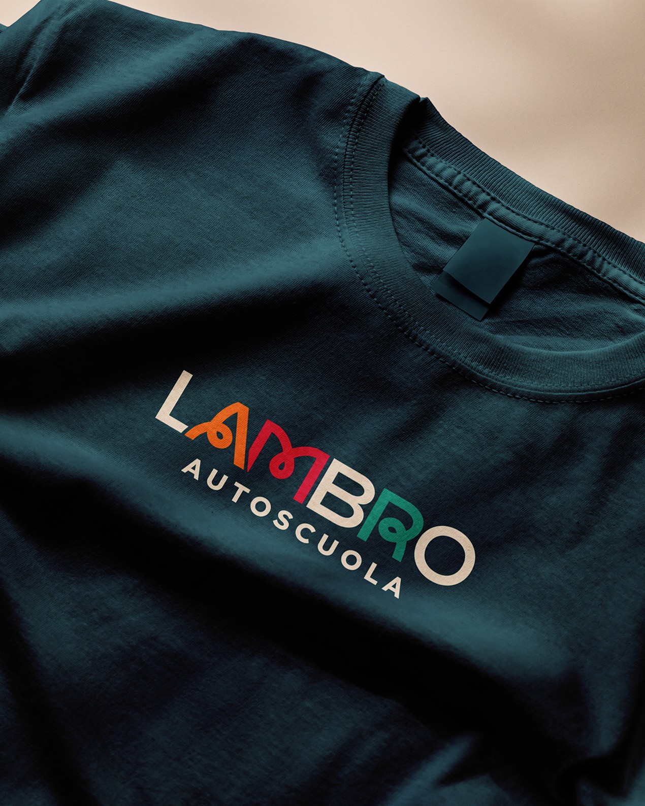 Dark teal T-shirt printed with the multicoloured Lambro Autoscuola logo