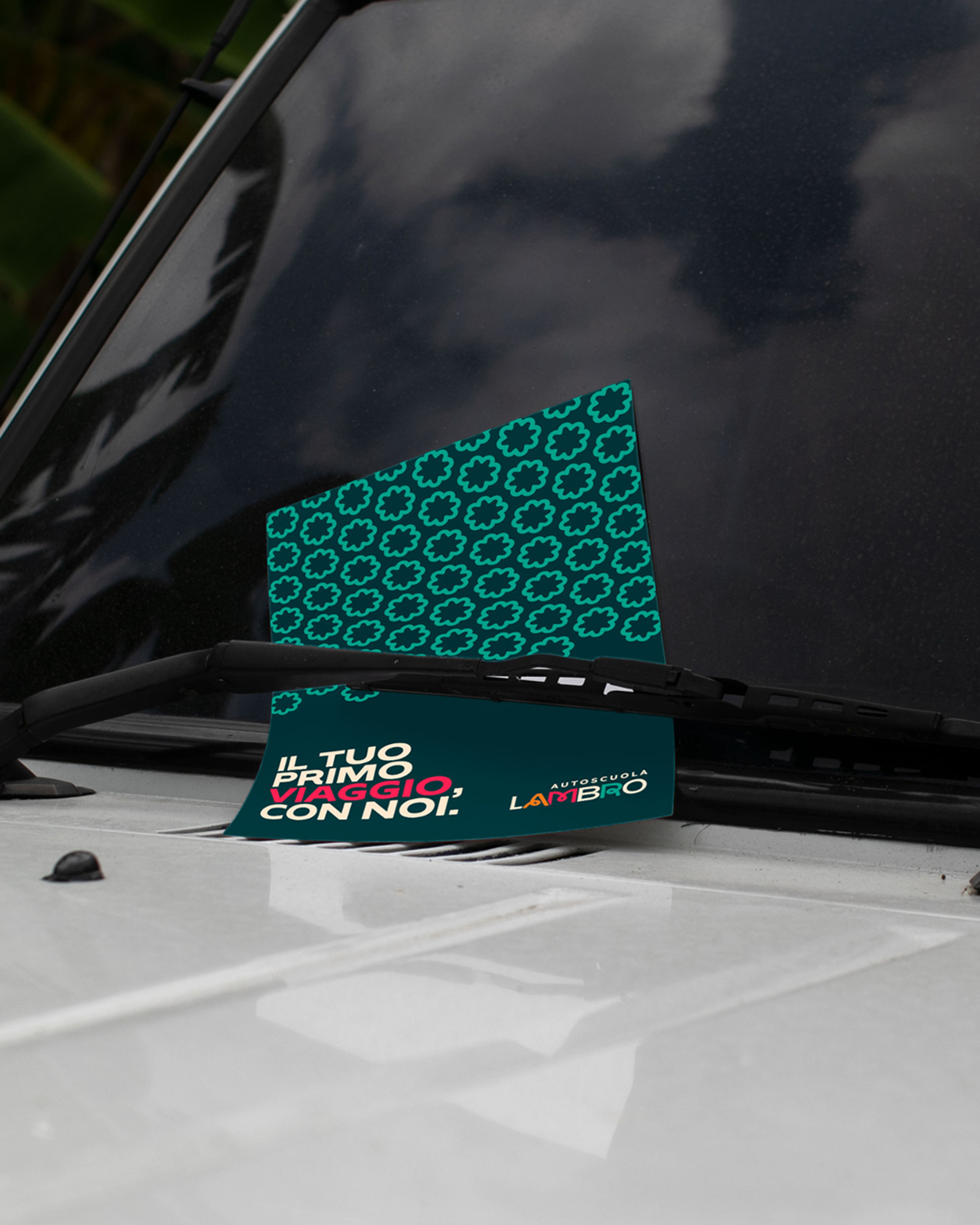 Autoscuola Lambro flyer reading Il tuo primo viaggio, con noi under a windscreen wiper