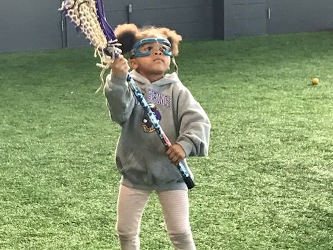 A young girl holding a lacrosse stick