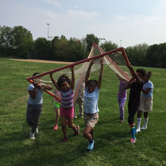 A group of girls holding up a soccer goal.