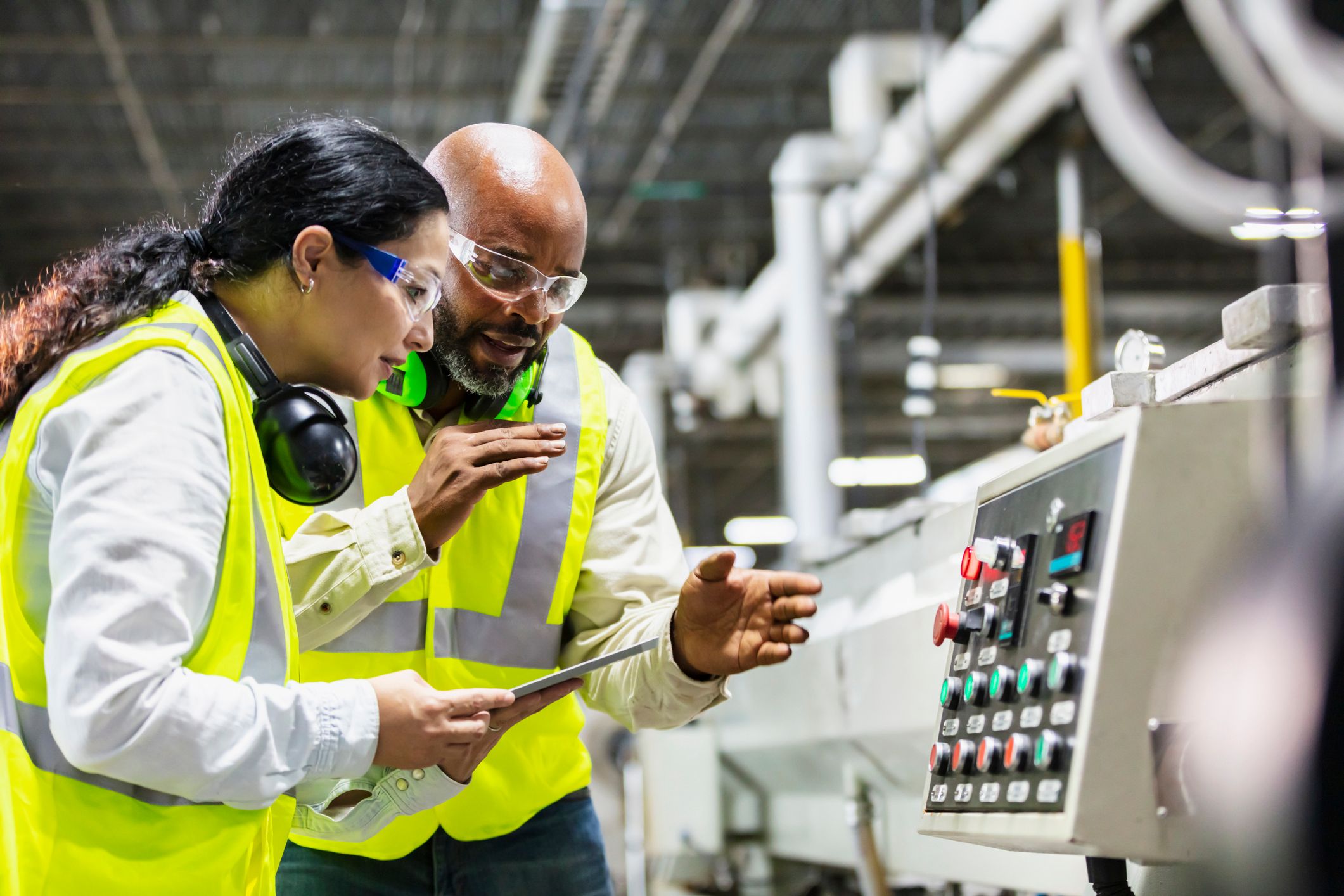 Two workers in factory consulting at a CNC machine