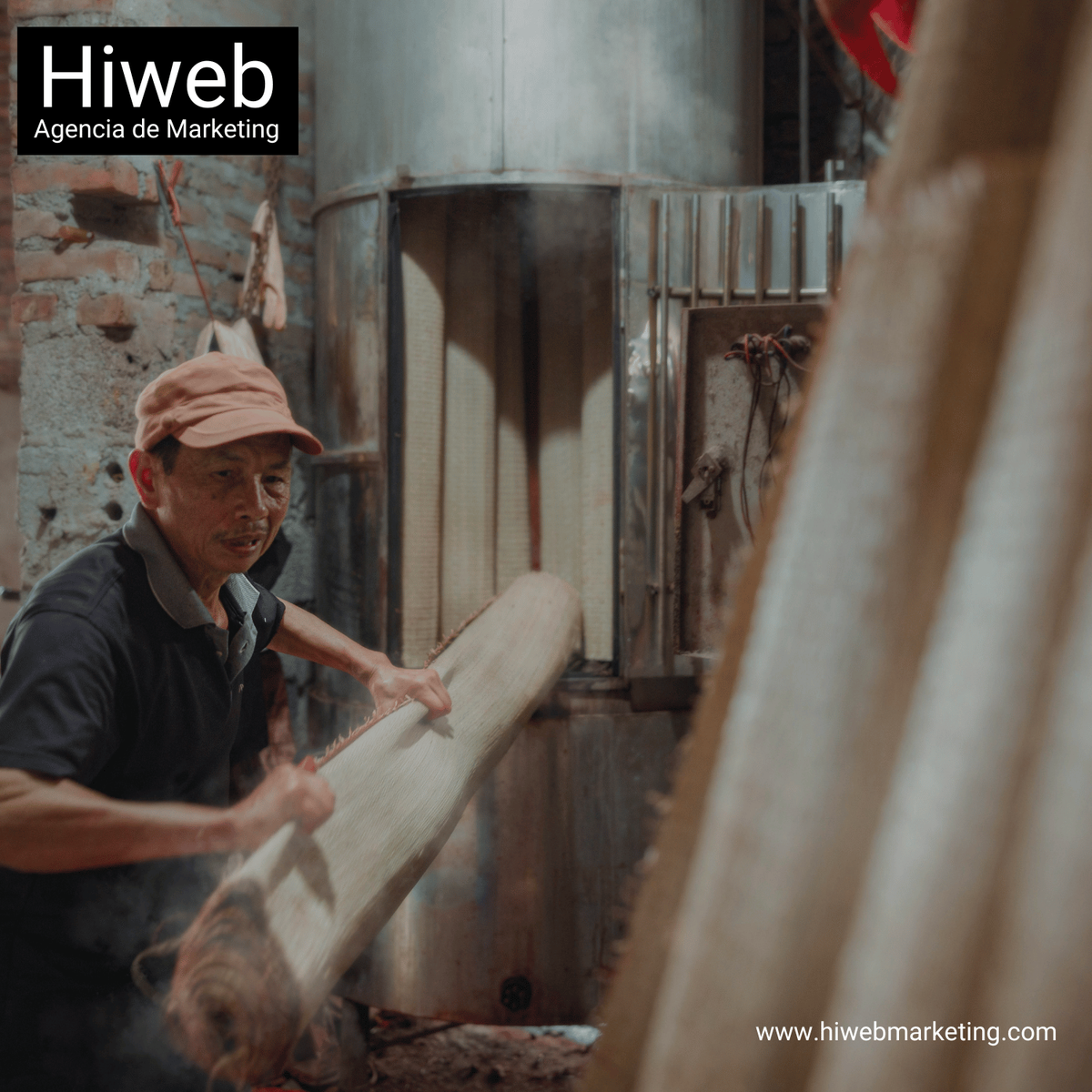 Hombre trabajando en un taller artesanal manipulando un rollo de material tejido, en un entorno rústico de producción manual. Hiweb Agencia de Marketing.