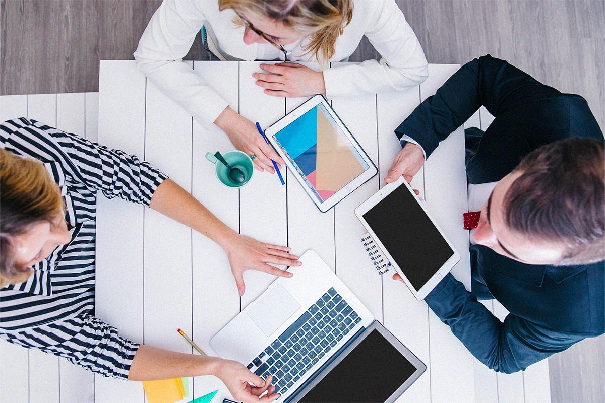 Profesionales trabajando en equipo con dispositivos tecnológicos para desarrollar estrategias digitales, innovación y crecimiento empresarial Hiweb.
