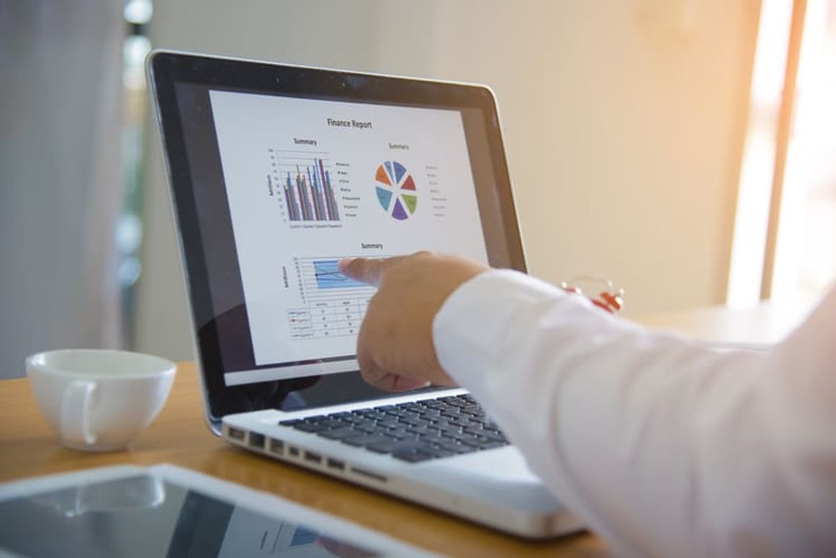Professional analyzing business reports and performance charts on a laptop, representing data-driven marketing decisions and digital strategy optimization Hiweb