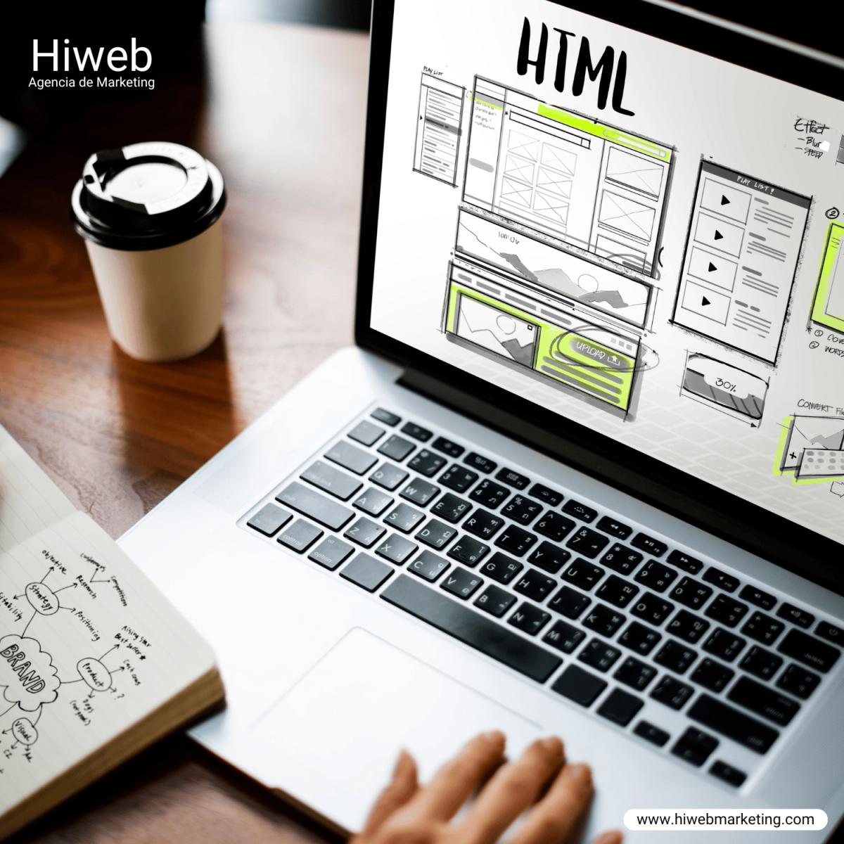 Laptop sobre escritorio con una taza de café, mostrando en pantalla bocetos de diseño web en HTML y wireframes de una interfaz digital, representando desarrollo web y UX/UI dentro del marketing digital, Hiweb.