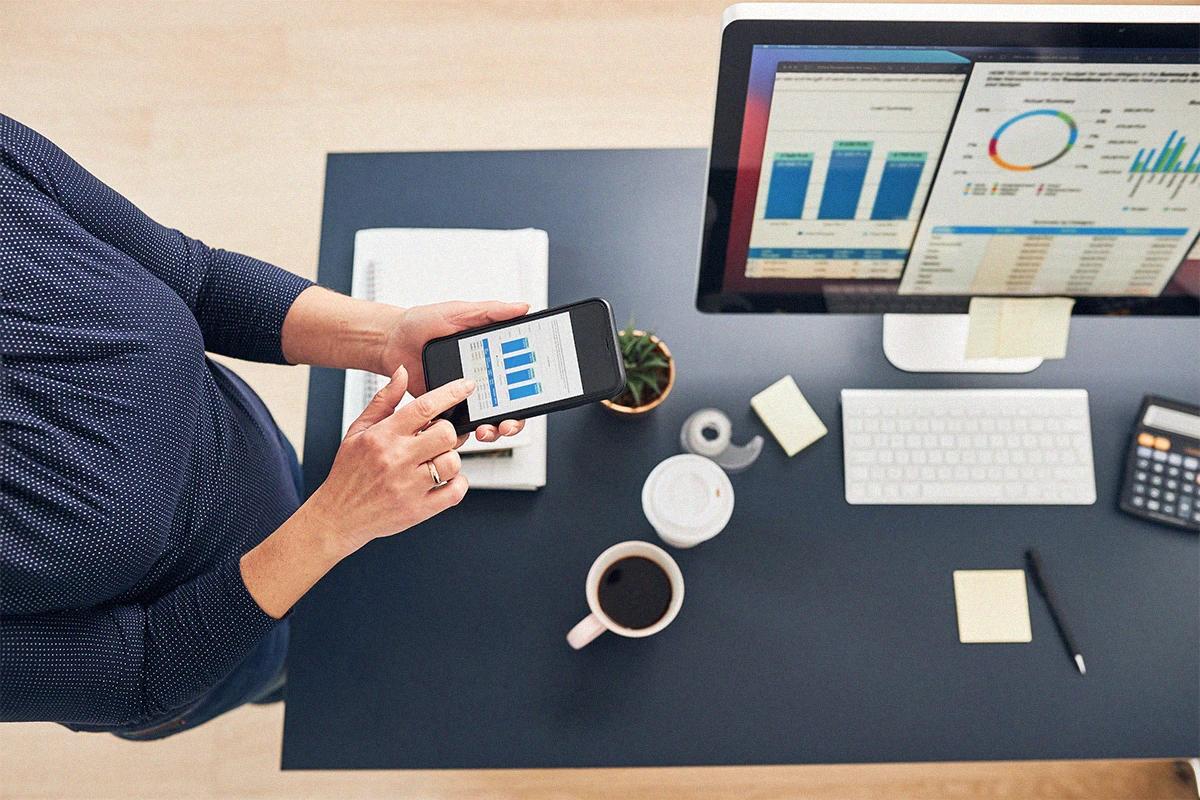 Person managing Google Ads metrics at a tidy desk, with charts visible on the computer screen